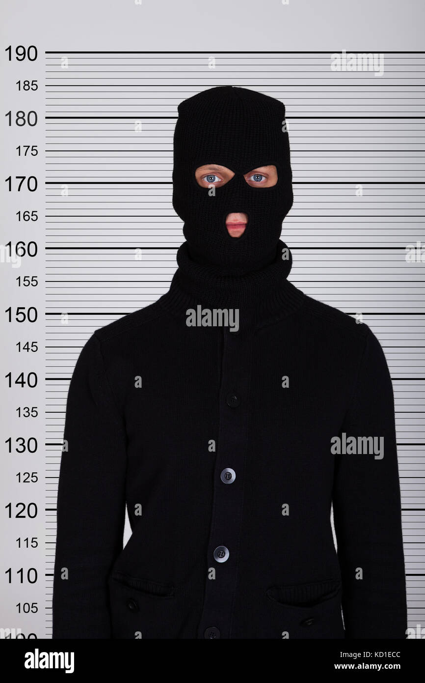 Burglar Wearing Balaclava Standing Against Police Lineup Stock Photo