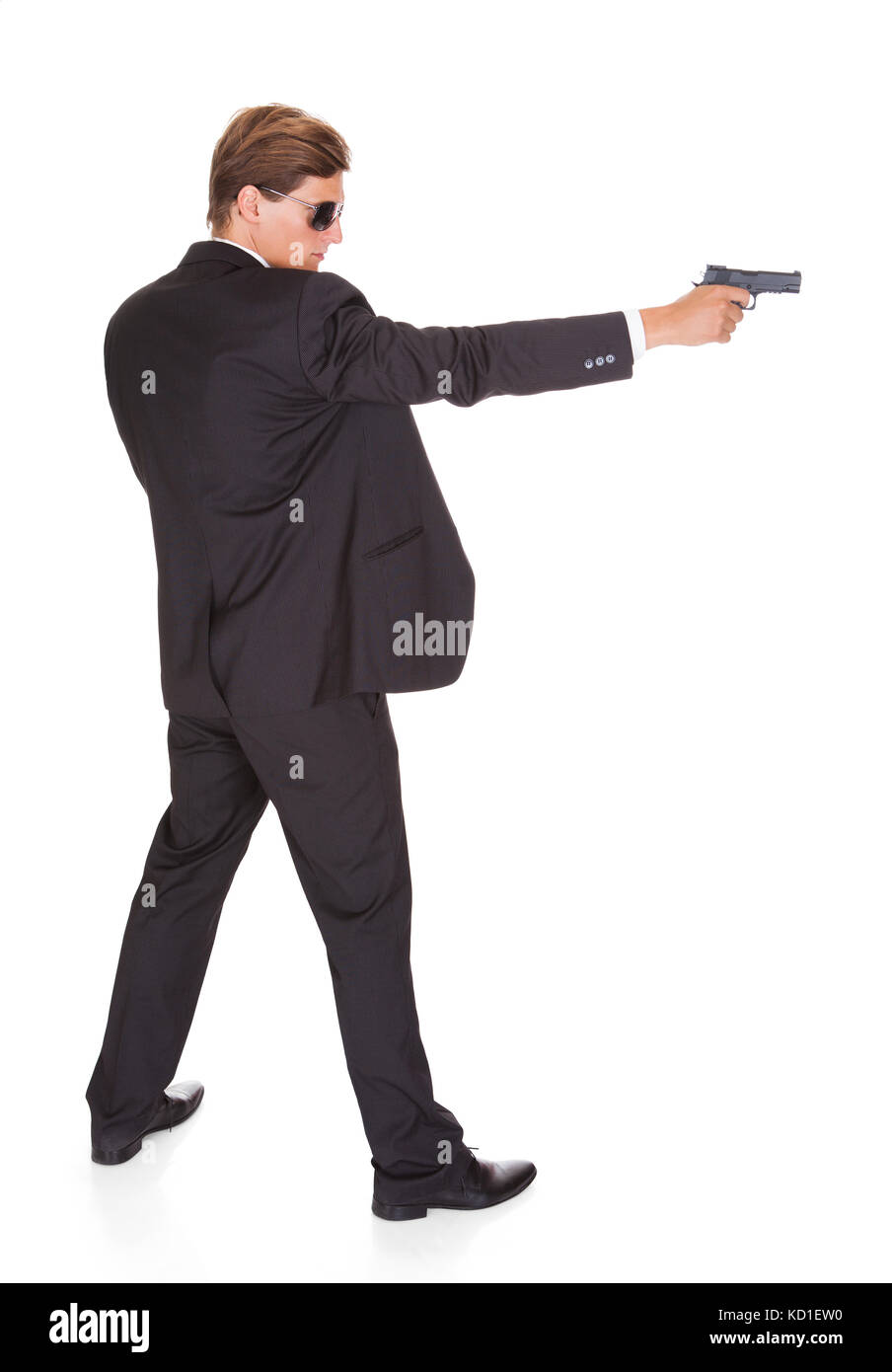Young Man In Black Suit Aiming With A Gun On White Background Stock Photo