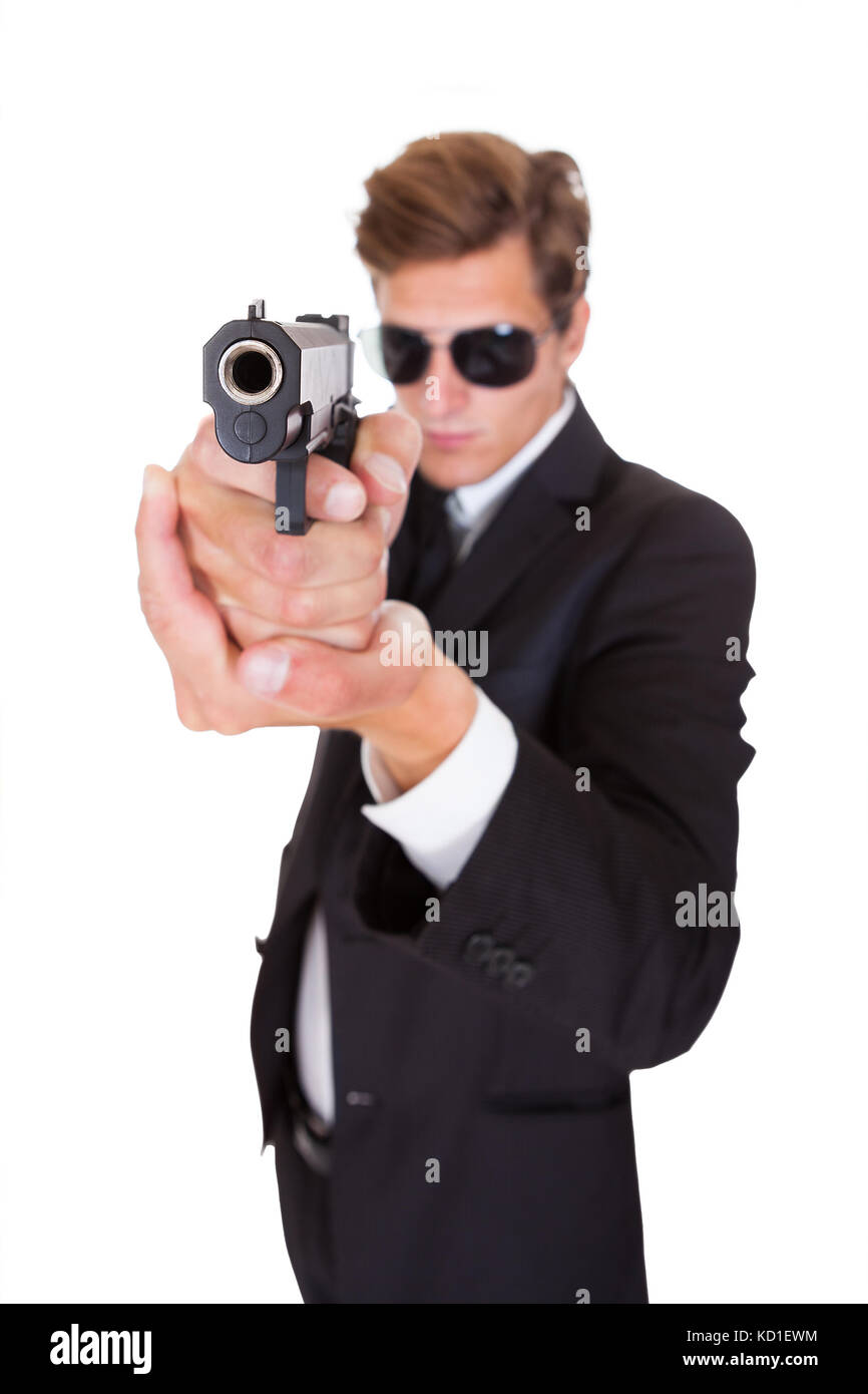 Young Man In Black Suit Aiming With A Gun On White Background Stock Photo