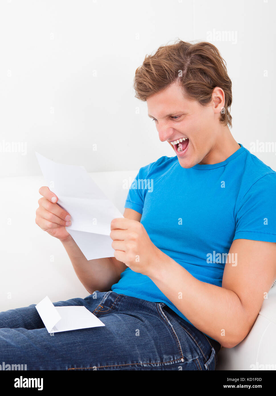 Excited Young Man Clenching His Fist Looking At Paper Stock Photo