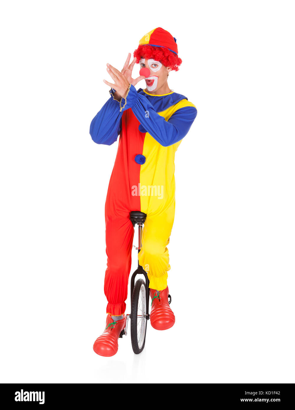 Portrait Of A Funny Clown Performing On Unicycle Over White Background Stock Photo