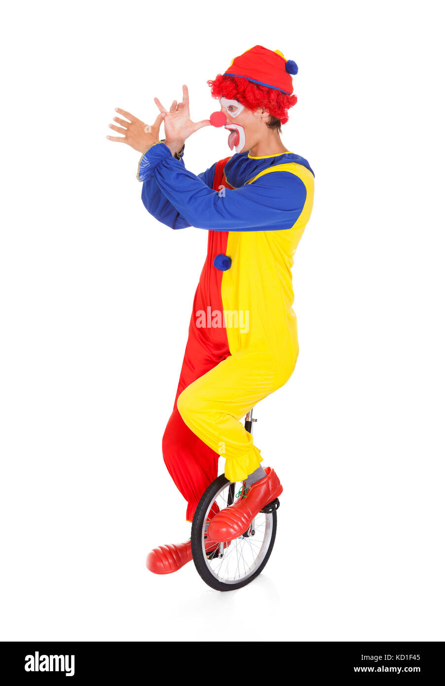 Portrait Of A Funny Clown Performing On Unicycle Over White Background Stock Photo