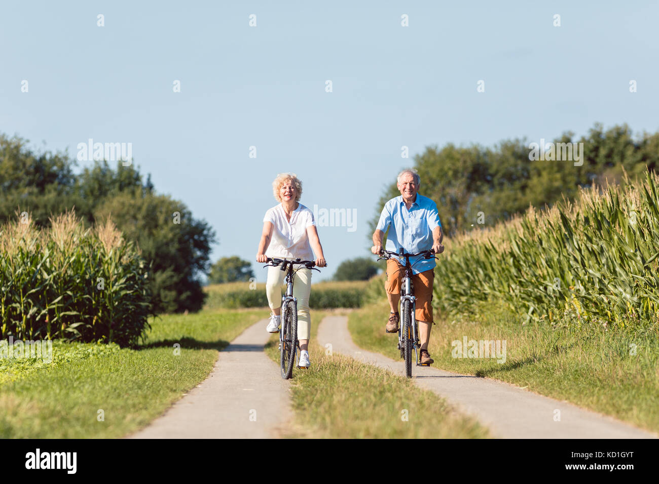 Senior couple looking forward with confidence while riding bicyc Stock Photo