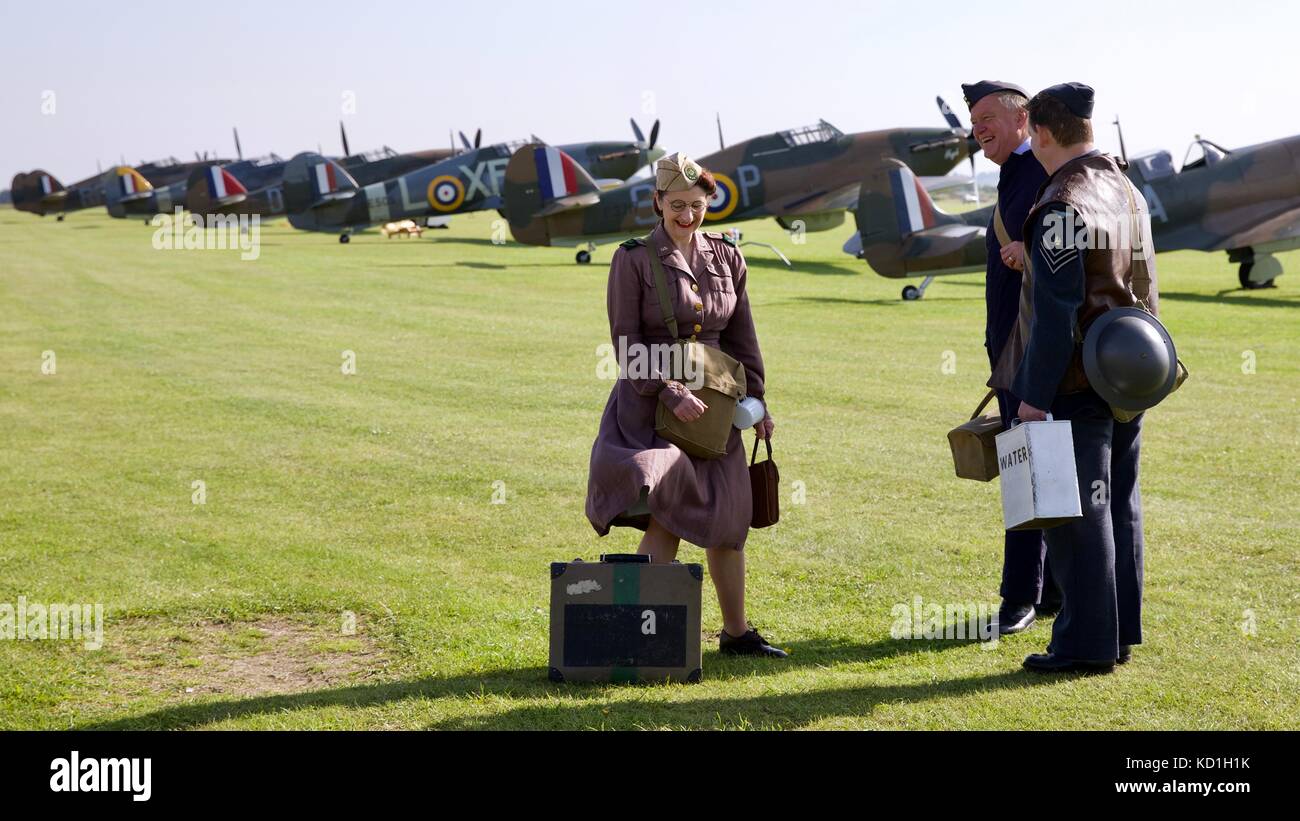 Three people dress in period uniforms on the flight line at IWM Duxford Stock Photo