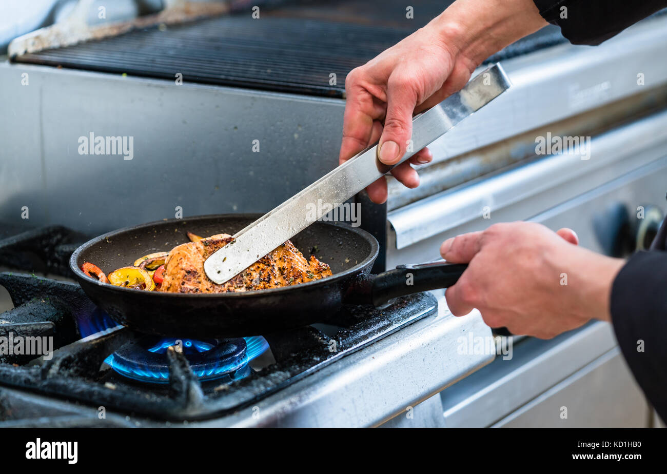 Chef turning fish in pan while cooking Stock Photo - Alamy
