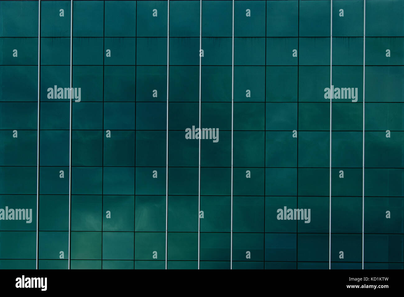 Reflective glass panels from a building, closeup, reflecting overcast sky, green and blue, lines, squares and rows, abstract background Stock Photo