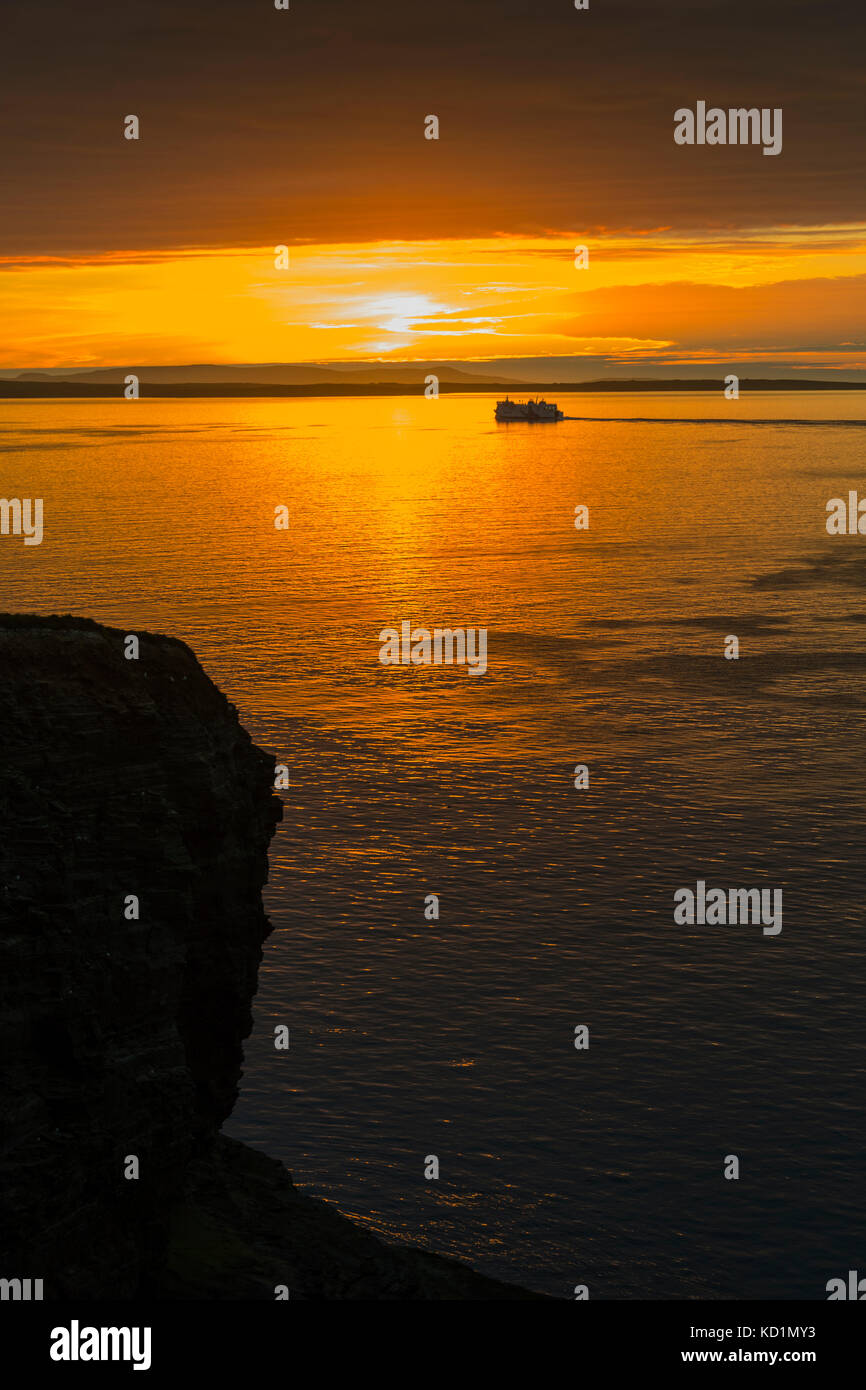 Tthe Northlink ferry, the MV Hrossey, passing Mull Head at sunset, Deerness, Orkney Mainland, Scotland, UK. Stock Photo