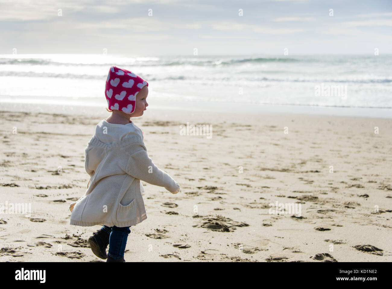 One-year-old girl walking on beach toward the ocean. Ocean Beach, San Francisco, California Stock Photo