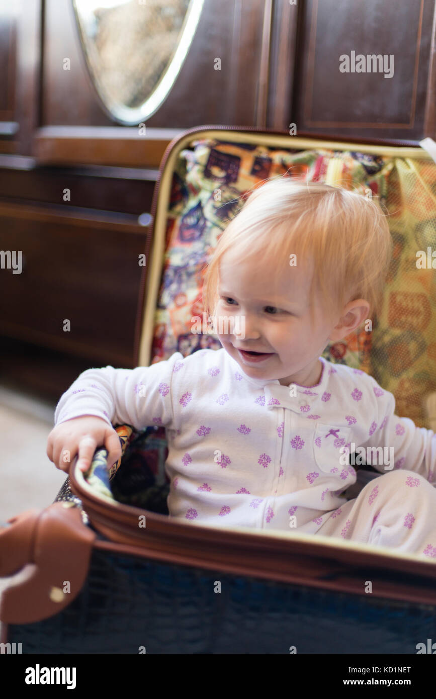 One-year-girl with blonde hari sitting inside a suitcase Stock Photo