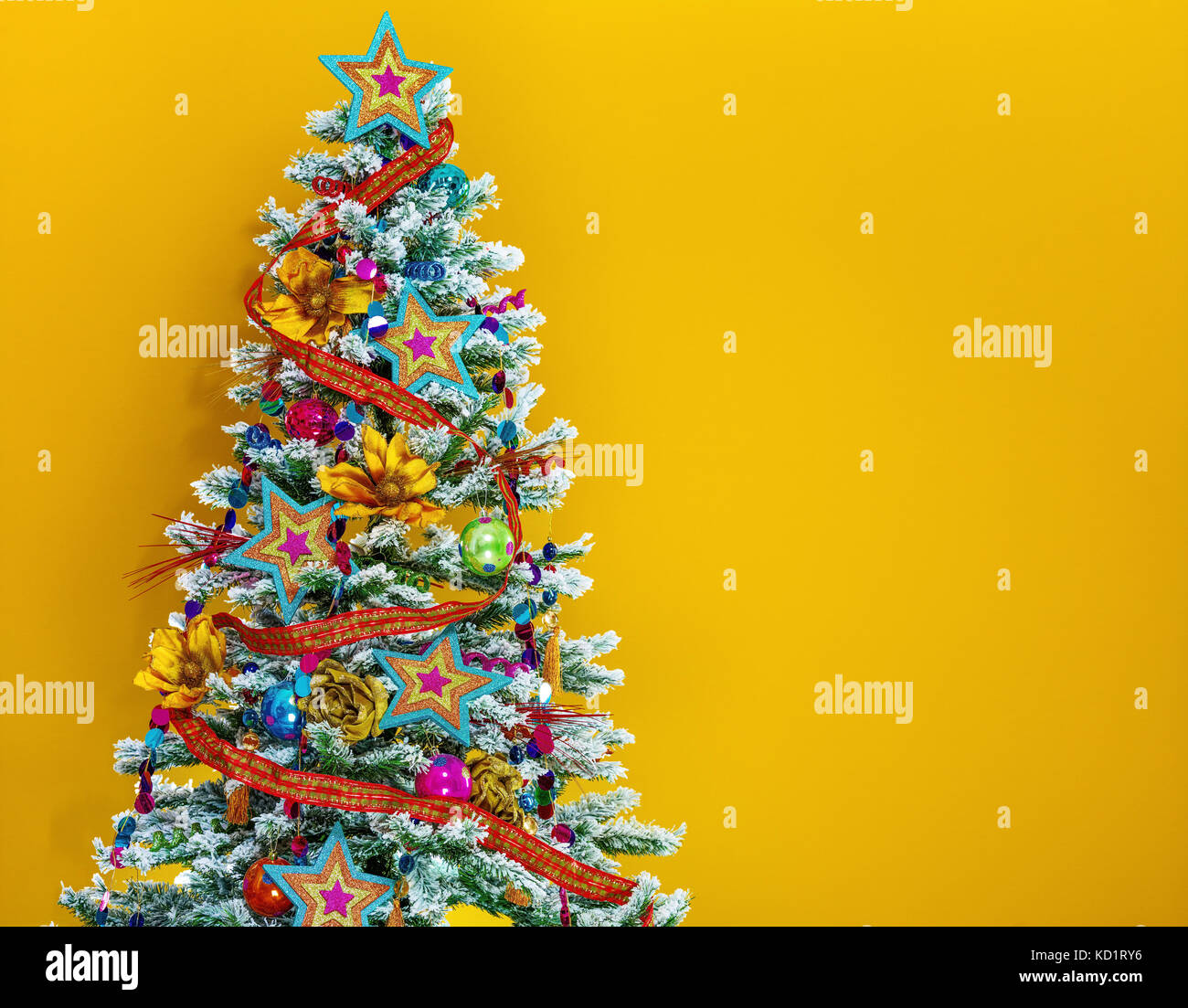 Festive season. colorful Christmas tree isolated on yellow background Stock Photo