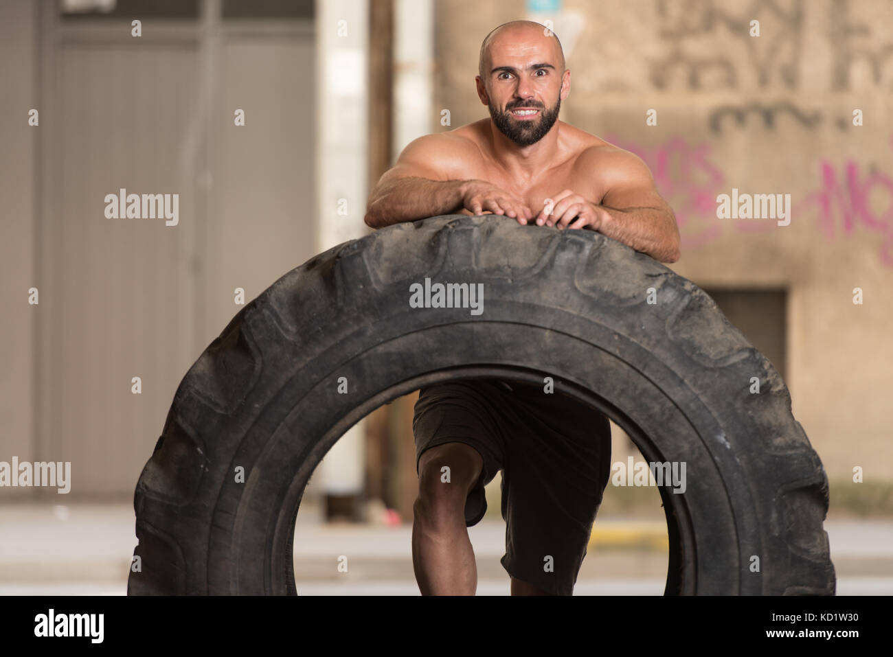 Young Muscular Man With Truck Tire Doing Crossfit Style Workout Turning