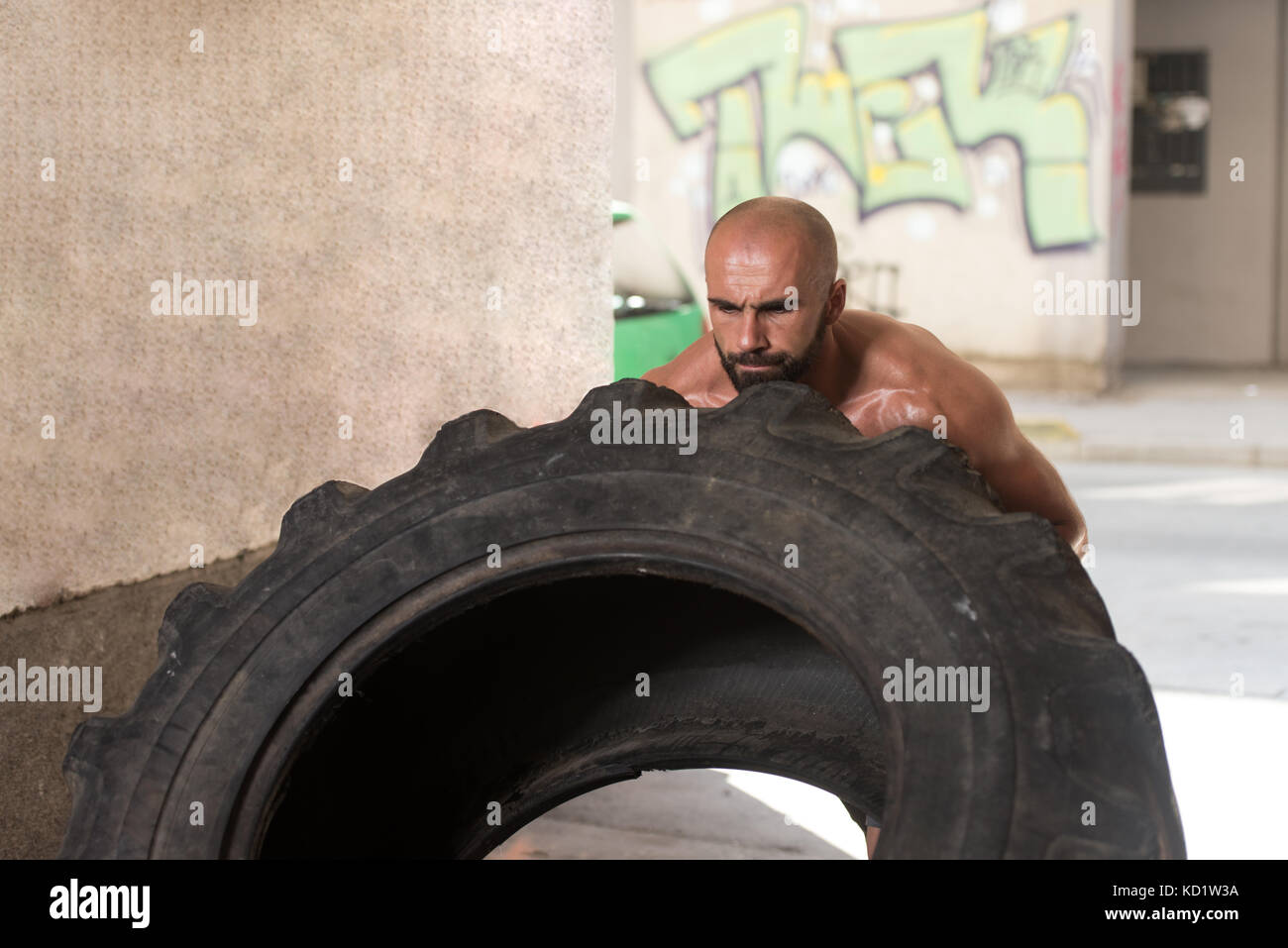 Young Muscular Man With Truck Tire Doing Crossfit Style Workout Turning