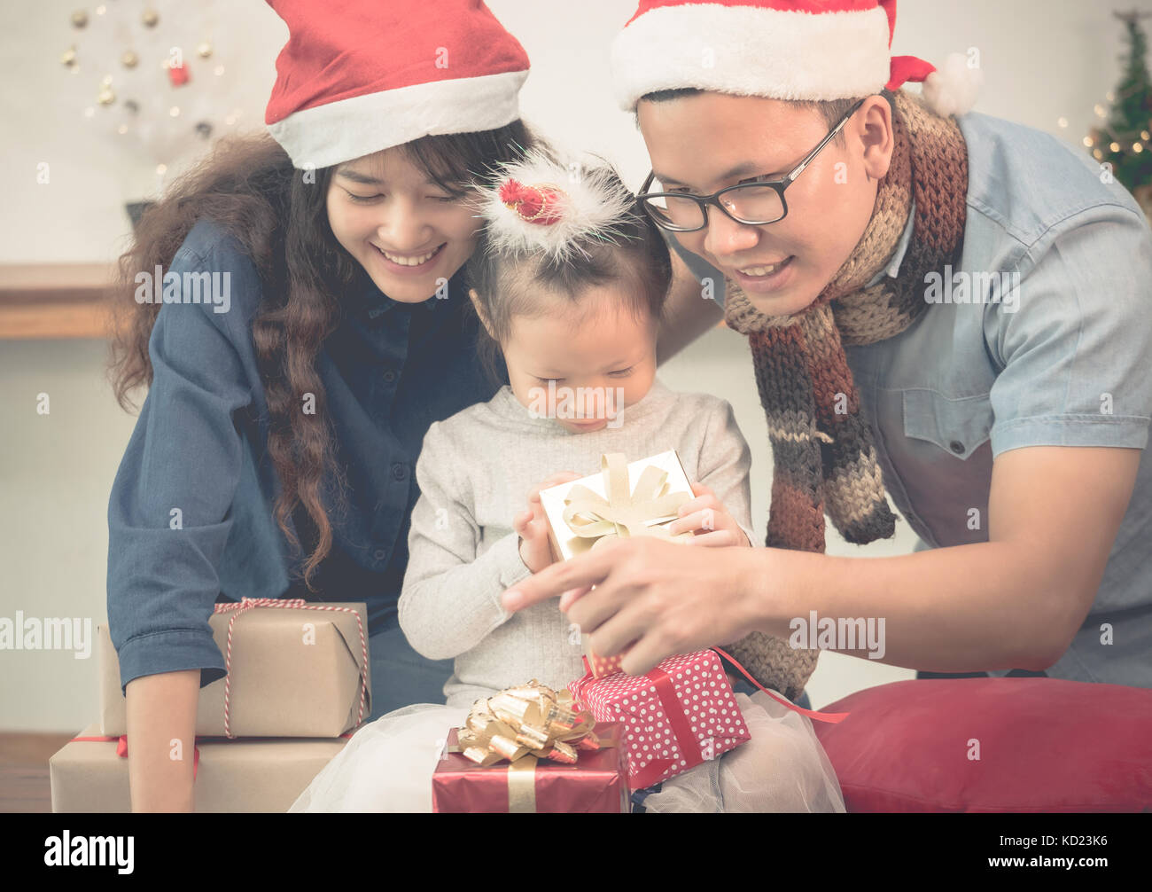 Happy family Asia family wear santa claus hat unwrap Christmas gift box at house xmas party,Holiday celebrating festive concept,vintage filter Stock Photo