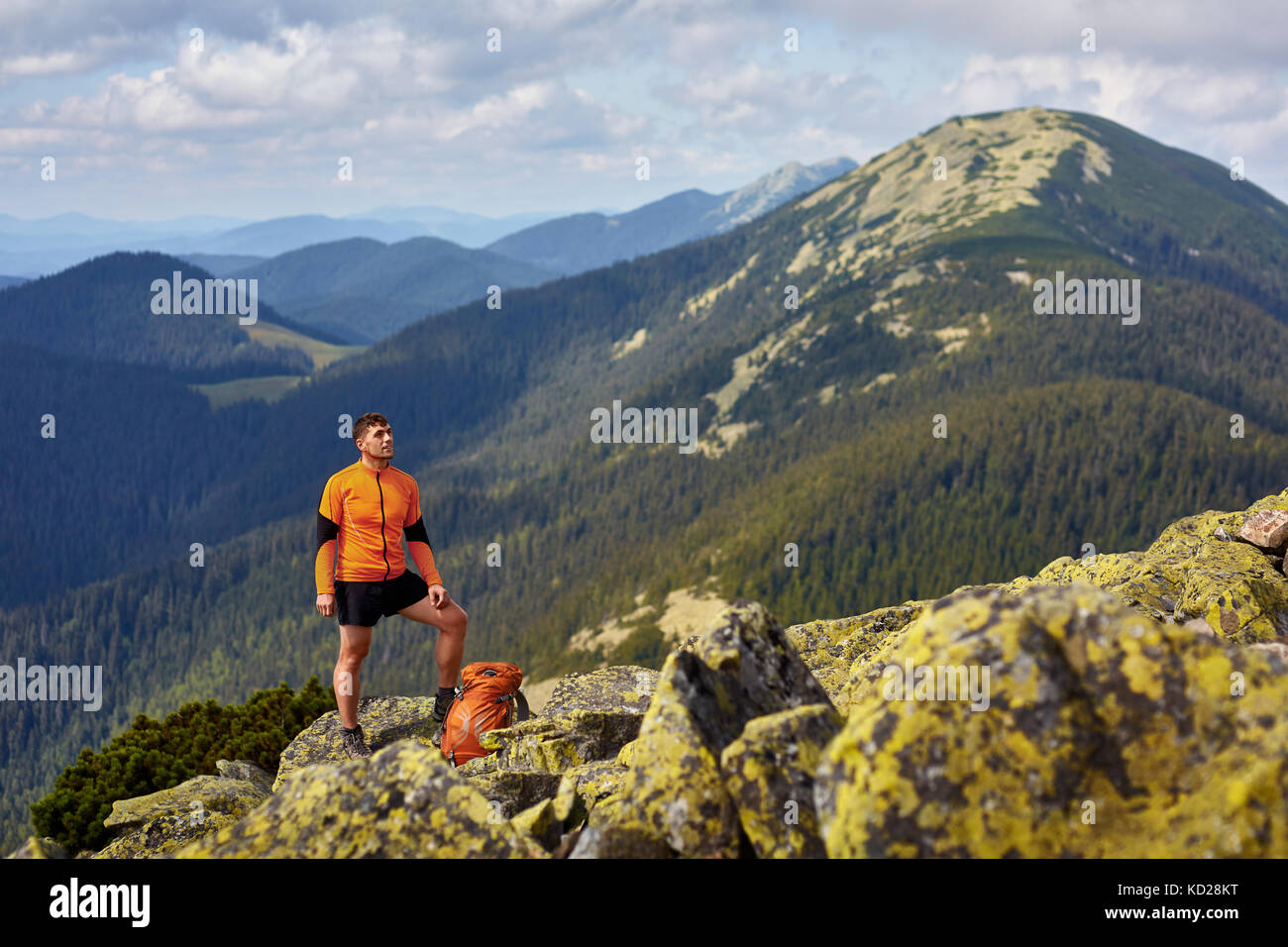 Hiker with backpack standing on top of a mountain with raised hands ...