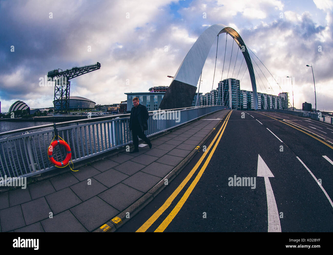 man walking over the Squinty Bridge in Glasgow, aka The Clyde Arc, with the Finnieston Crane , SSE Hydro and SECC Armadillo in the background Stock Photo