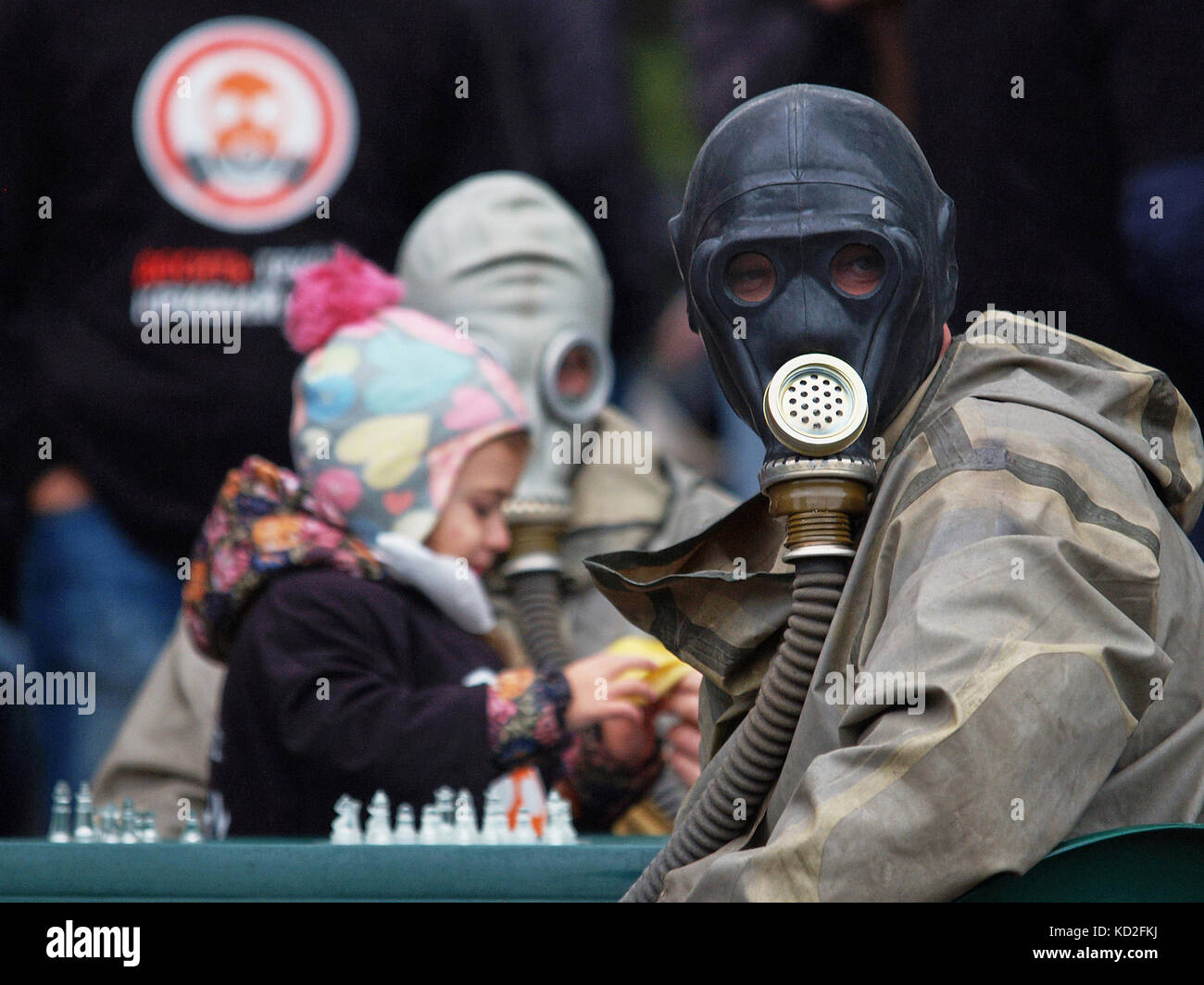 Kryvyi Rih, Ukraine - October 9, 2017: Man wearing black gas mask with little girl playing chess next to father during protest meeting near the ArcelorMittal Kryvyi Rih PJSC claim to reduce air pollution and conduct an independent audit of cleaning equipement at steel factory Credit: Dmytro Aliokhin/Alamy Live News Stock Photo