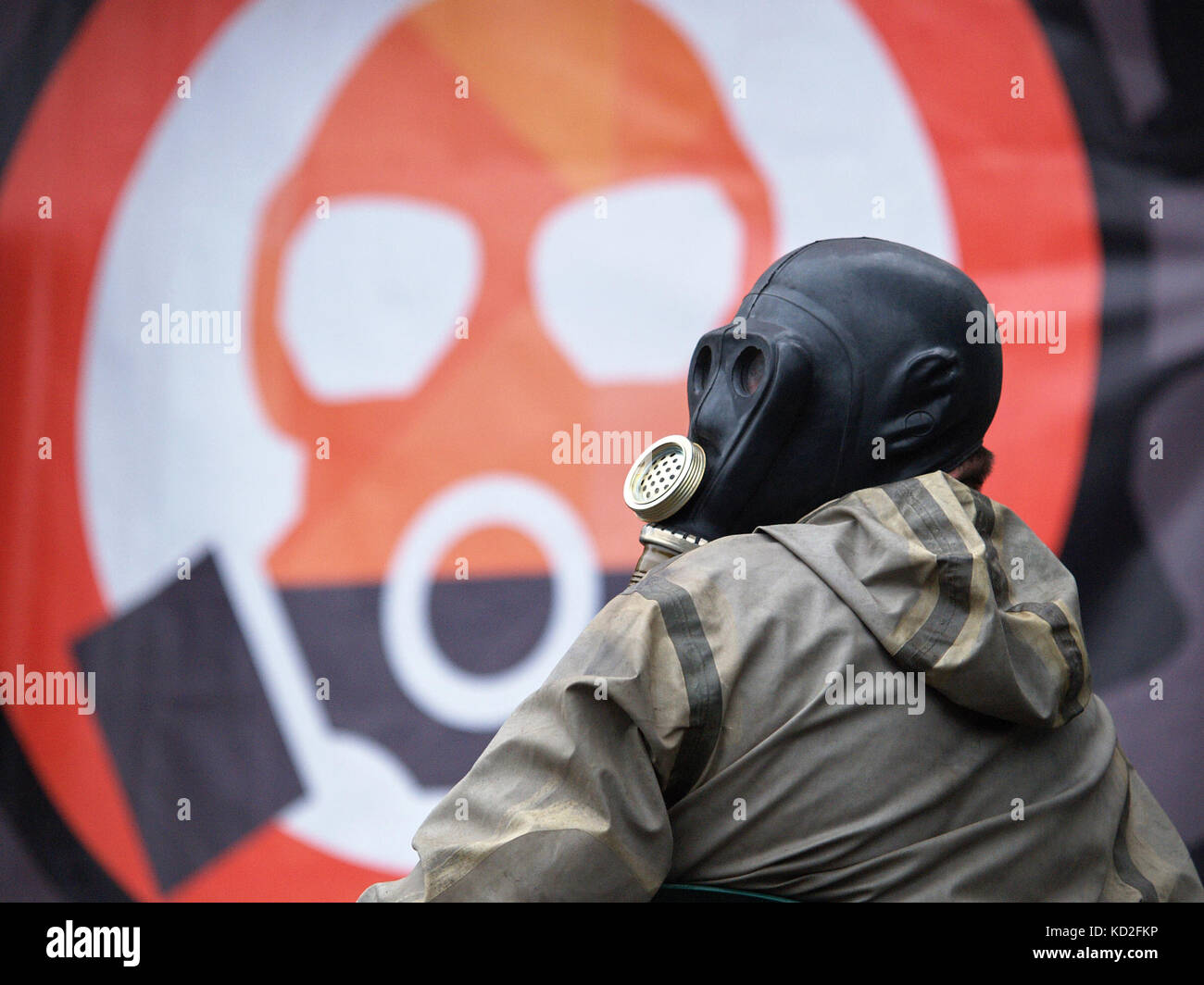 Kryvyi Rih, Ukraine - October 9, 2017: Man wearing black gas mask against poster with schematic gas mask during protest meeting near the ArcelorMittal Kryvyi Rih PJSC claim to reduce air pollution and conduct an independent audit of cleaning equipement at steel factory Credit: Dmytro Aliokhin/Alamy Live News Stock Photo