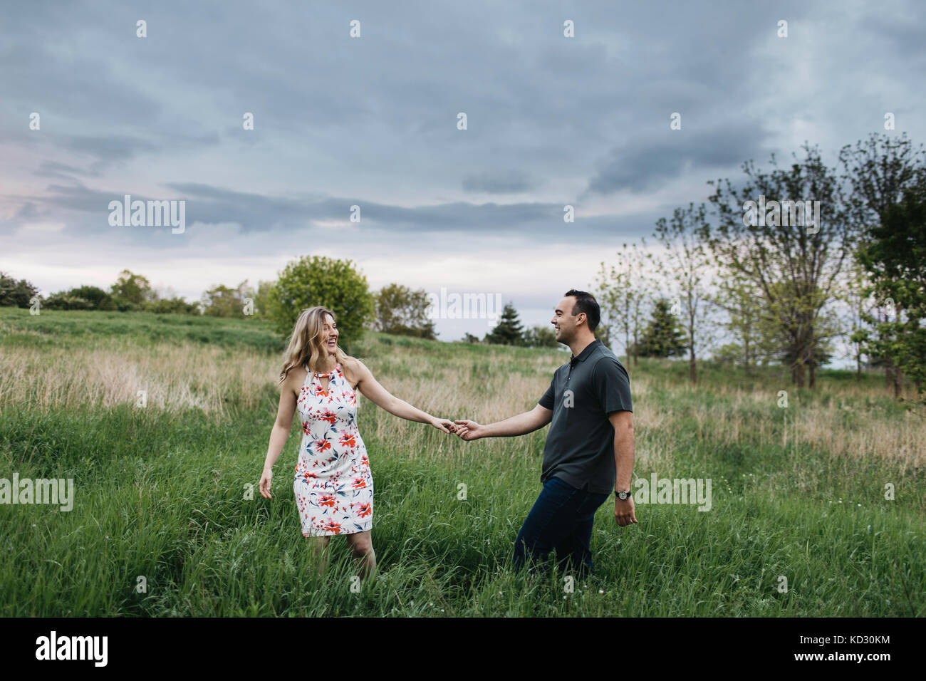 Romantic couple holding hands in field Stock Photo