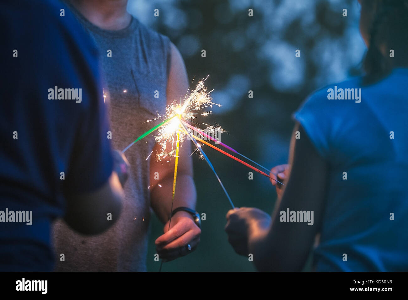 Cropped shot of women and girl igniting sparklers together at dusk on ...