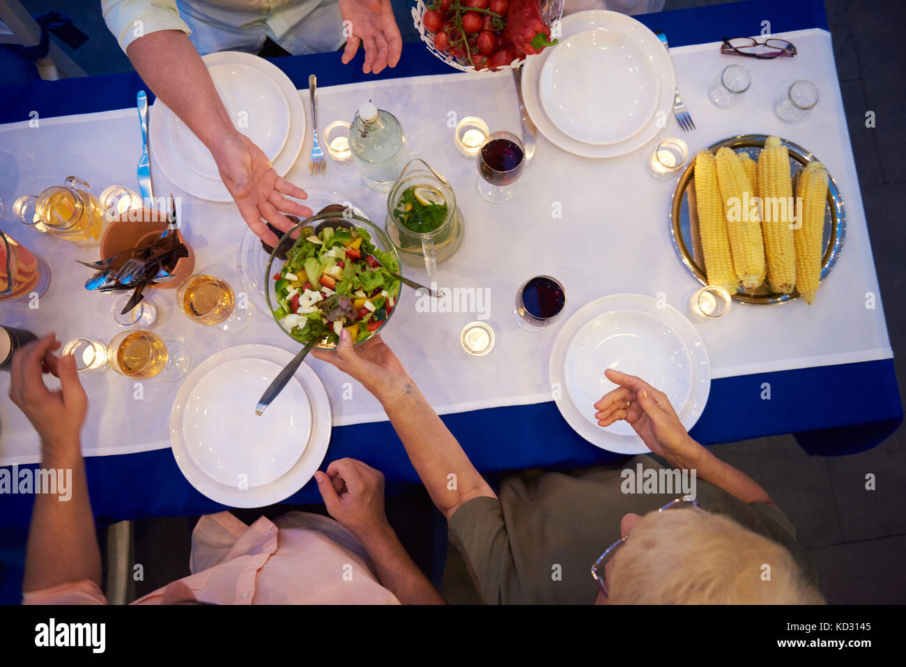 Group of people sitting at table, about to serve food, overhead view Stock Photo