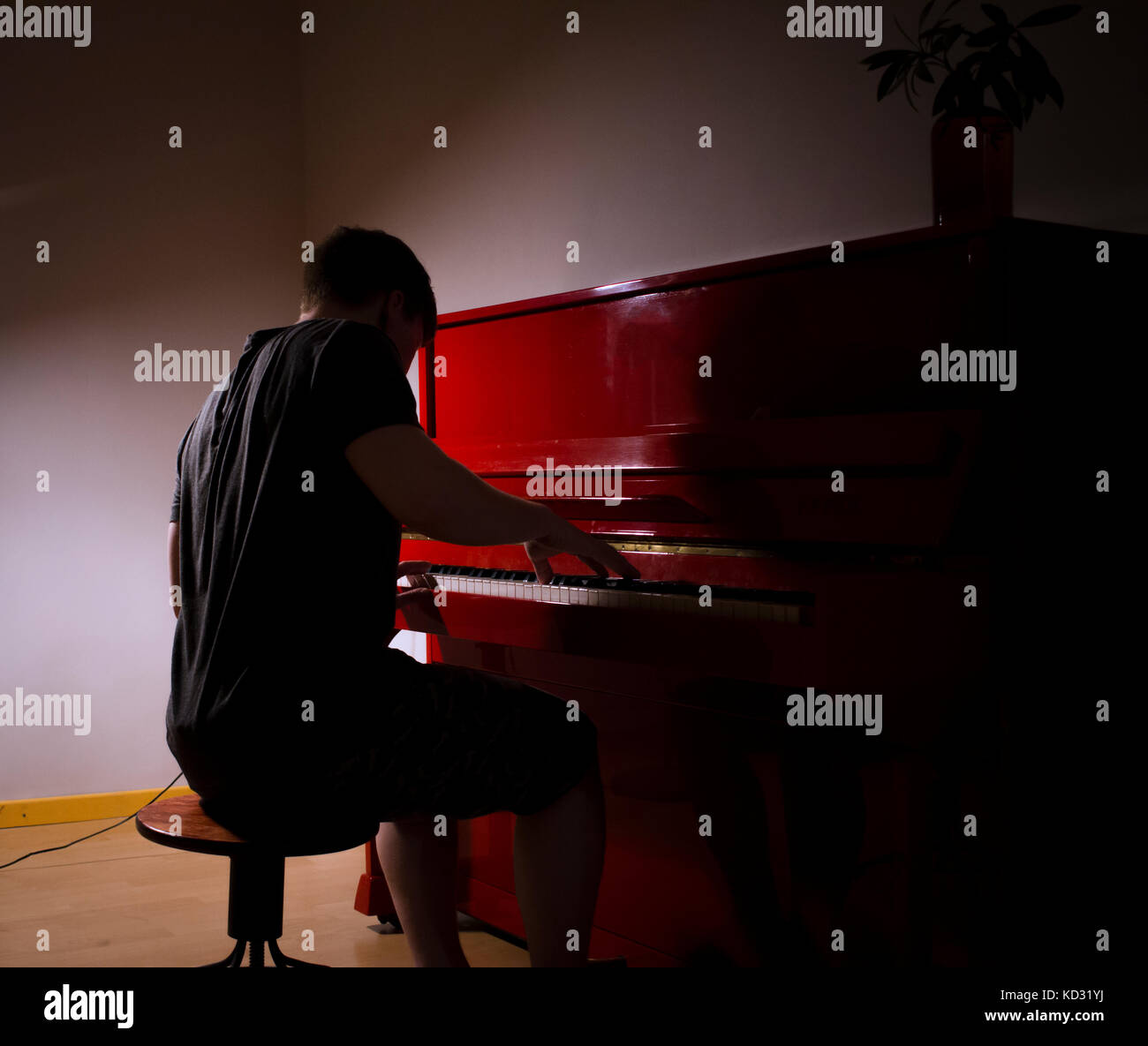 Man playing piano in dimly lit room Stock Photo