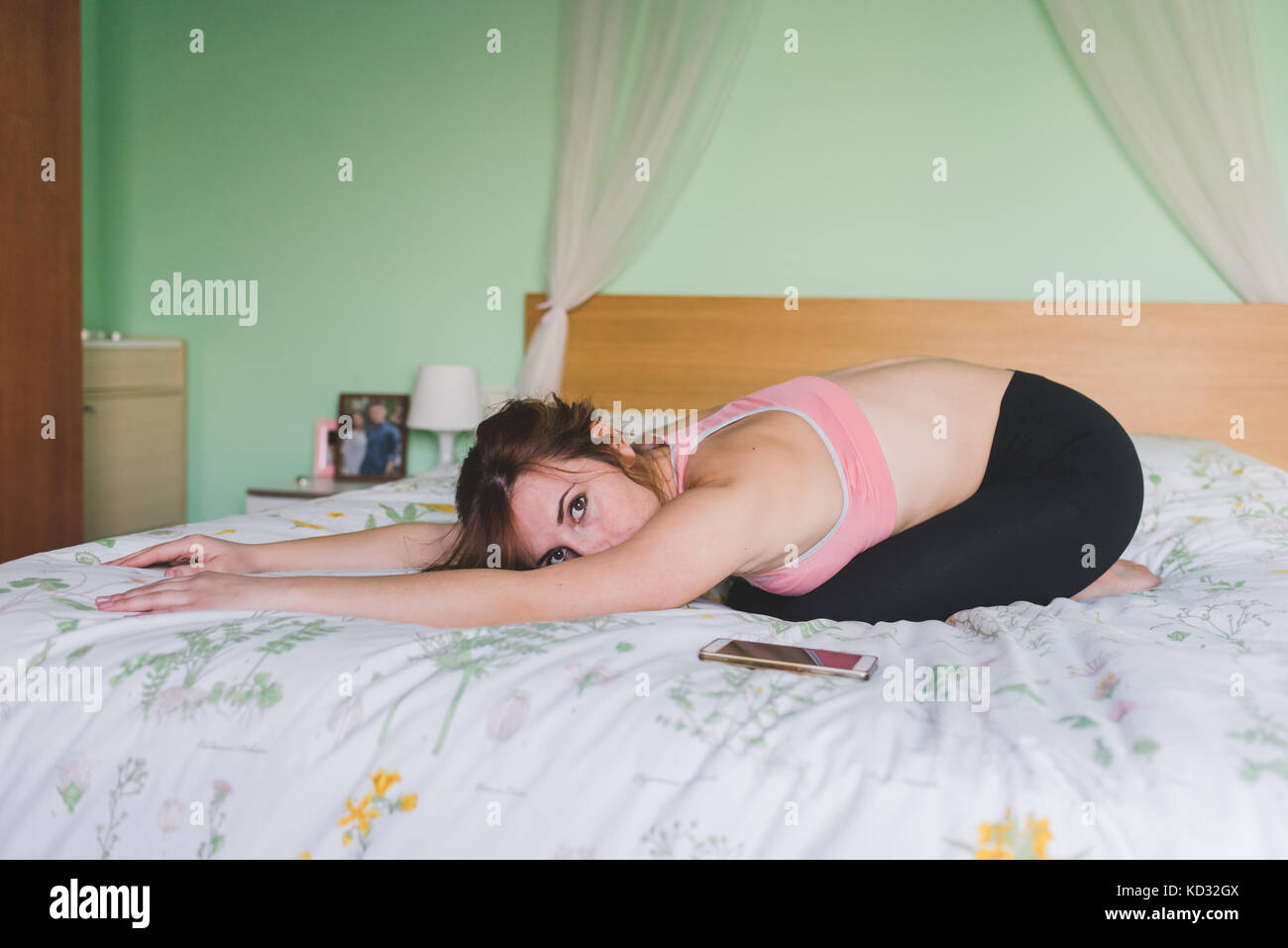 Young woman practicing yoga bending forward on bed Stock Photo - Alamy