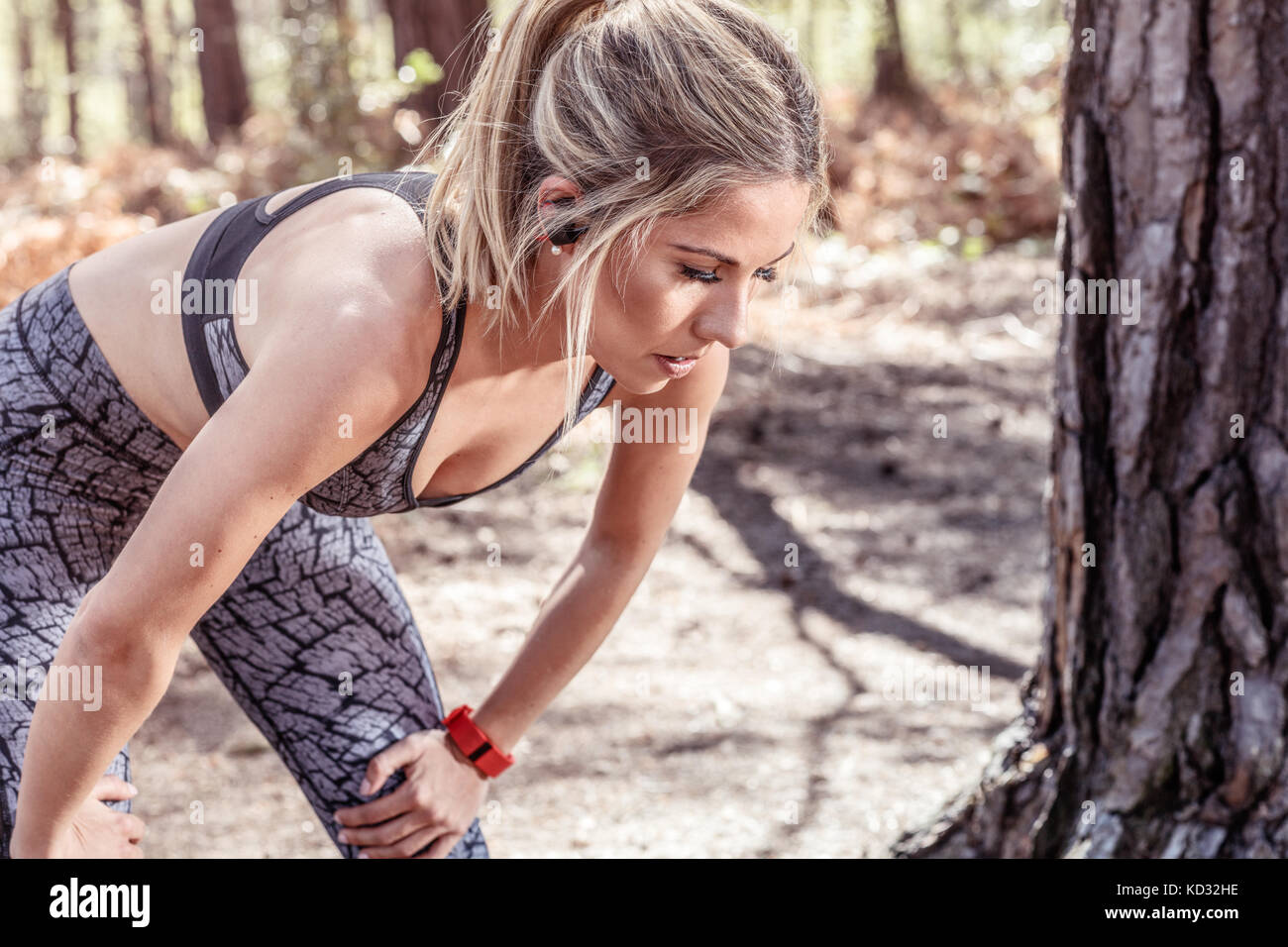 Young woman in rural setting, wearing sports clothing, hands on knees Stock Photo