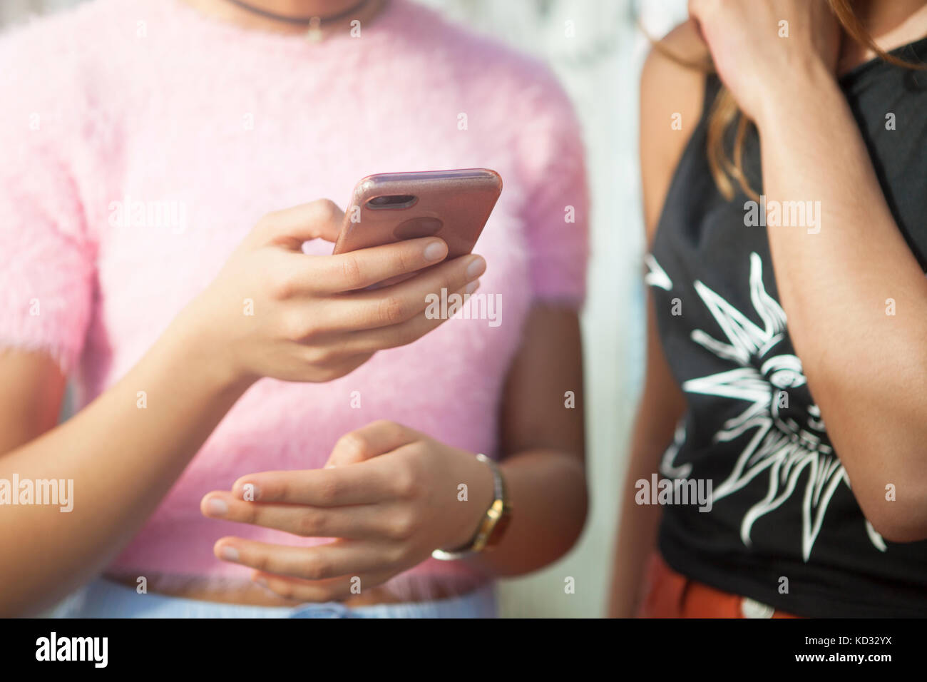 Two young women in street, looking at smartphone, mid section Stock Photo