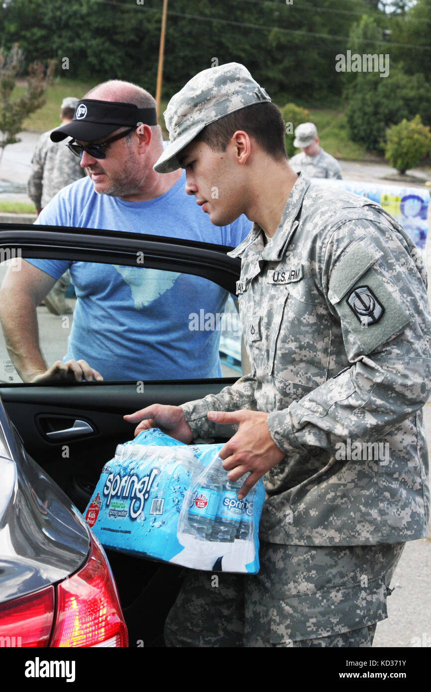 S.C. National Guard Soldier, Pvt. 1st Class Stanley Davidge, A Co., 151st Expeditionary Signal Battalion, from Greenwood, carries bottled water to vehicles Oct. 8, at a distribution site in Columbia. Guardsmen have been assisting with water distribution at numerous sites throughout the state after the worst rains and flooding in recorded history. The S.C. National Guard was on call before the storms hit and continued to provide support to the state’s citizens and fulfilled requests from the governor and other state authorities. (Photo by Sgt. Brad Mincey, 108th Public Affairs Detachment/Releas Stock Photo