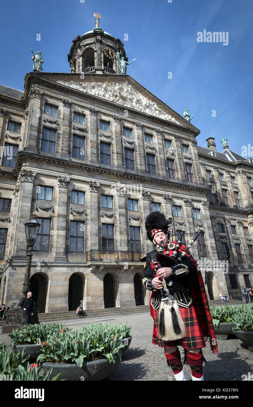 A piper in Scots costume incongruously plays outside the Royal Palace in Dam Square, Amsterdam Stock Photo