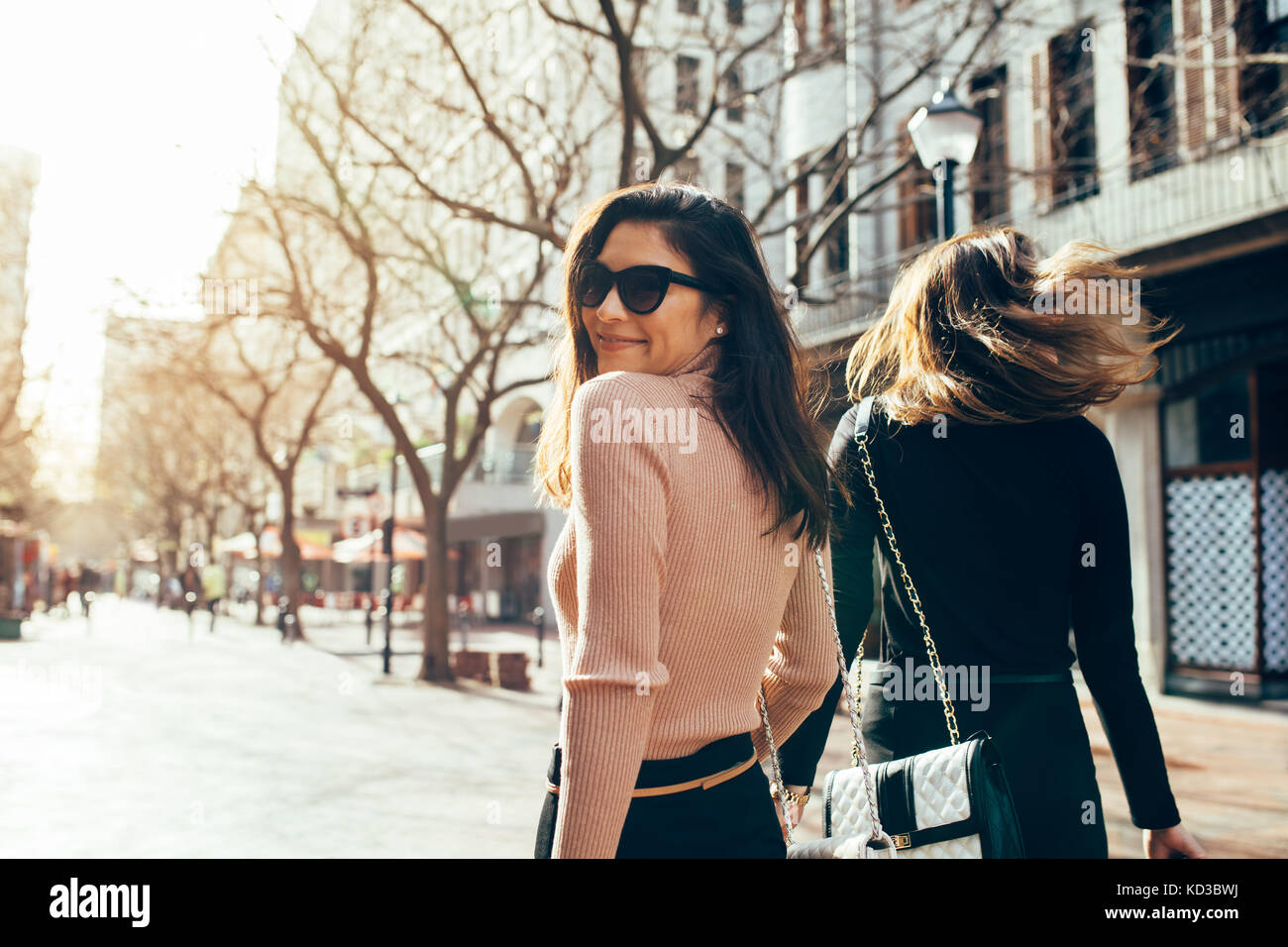 Asian woman walking with her friend on the city street. Two young women walking together outdoors on road. Stock Photo
