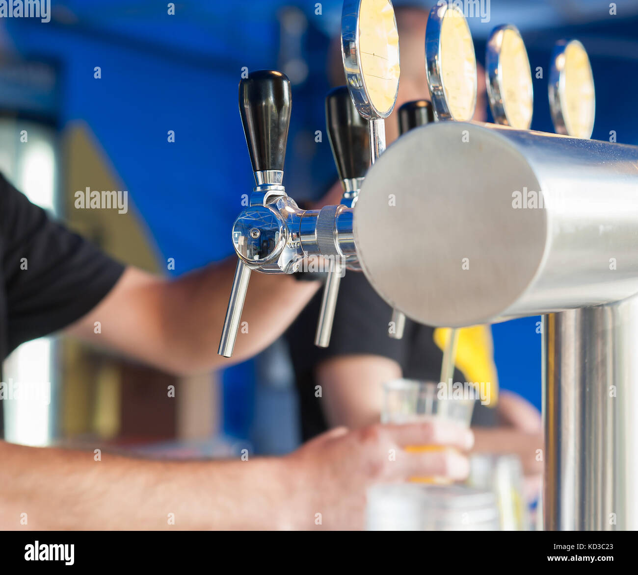 Barman hand at beer tap pouring a draught lager beer serving in a restaurant or pub. Stock Photo