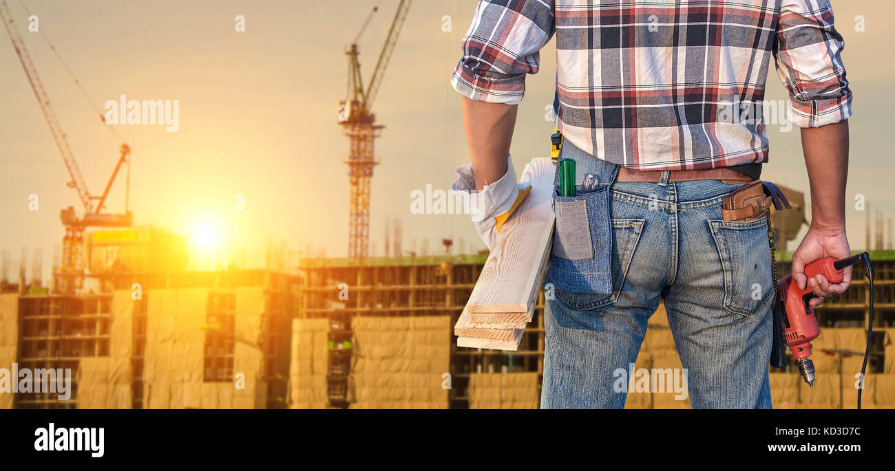 Construction worker. Builder handyman with drill and wooden plank. Stock Photo