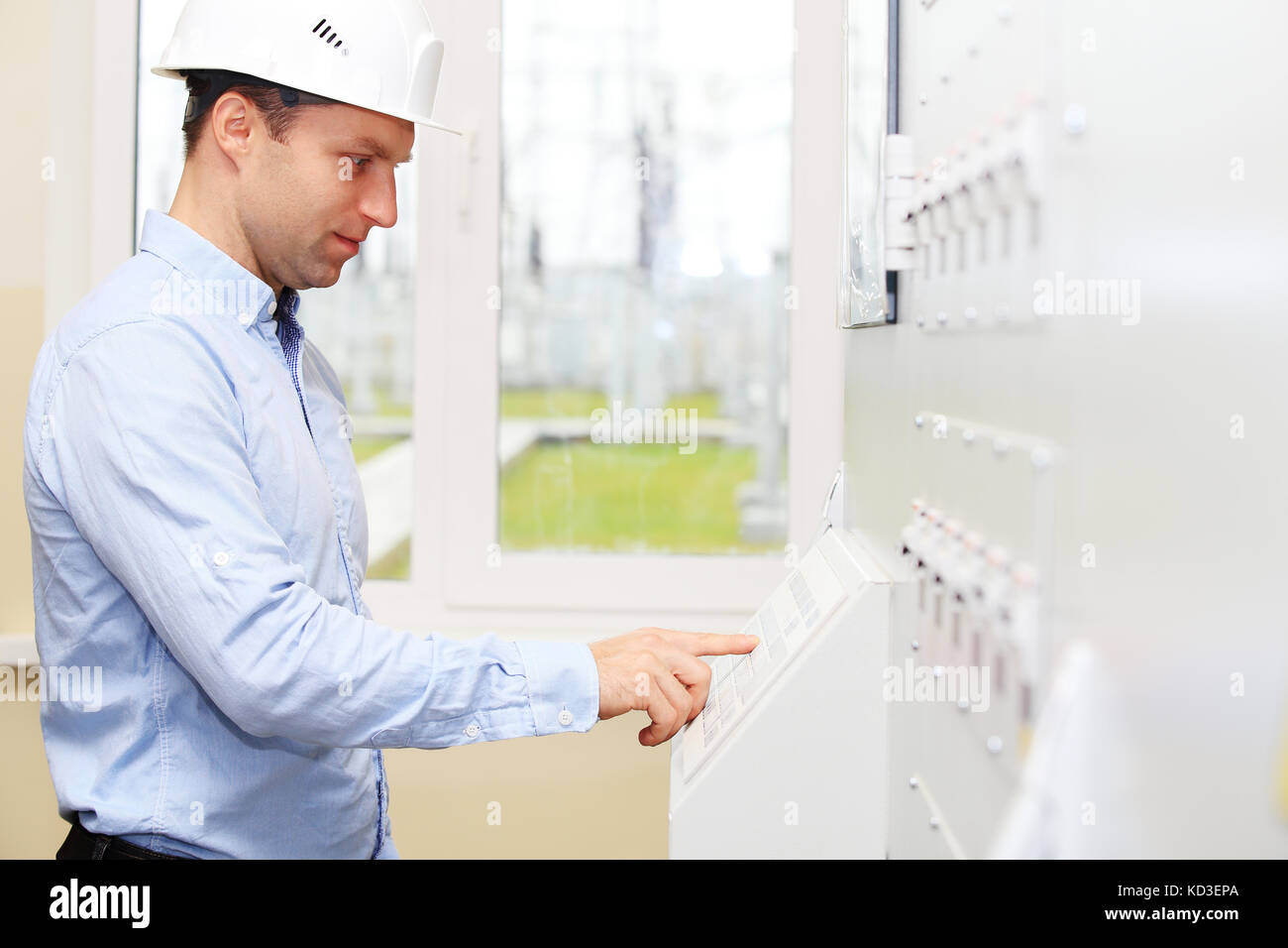 Young engineer checking energy system parameters. Electrician at modern power plant. Stock Photo