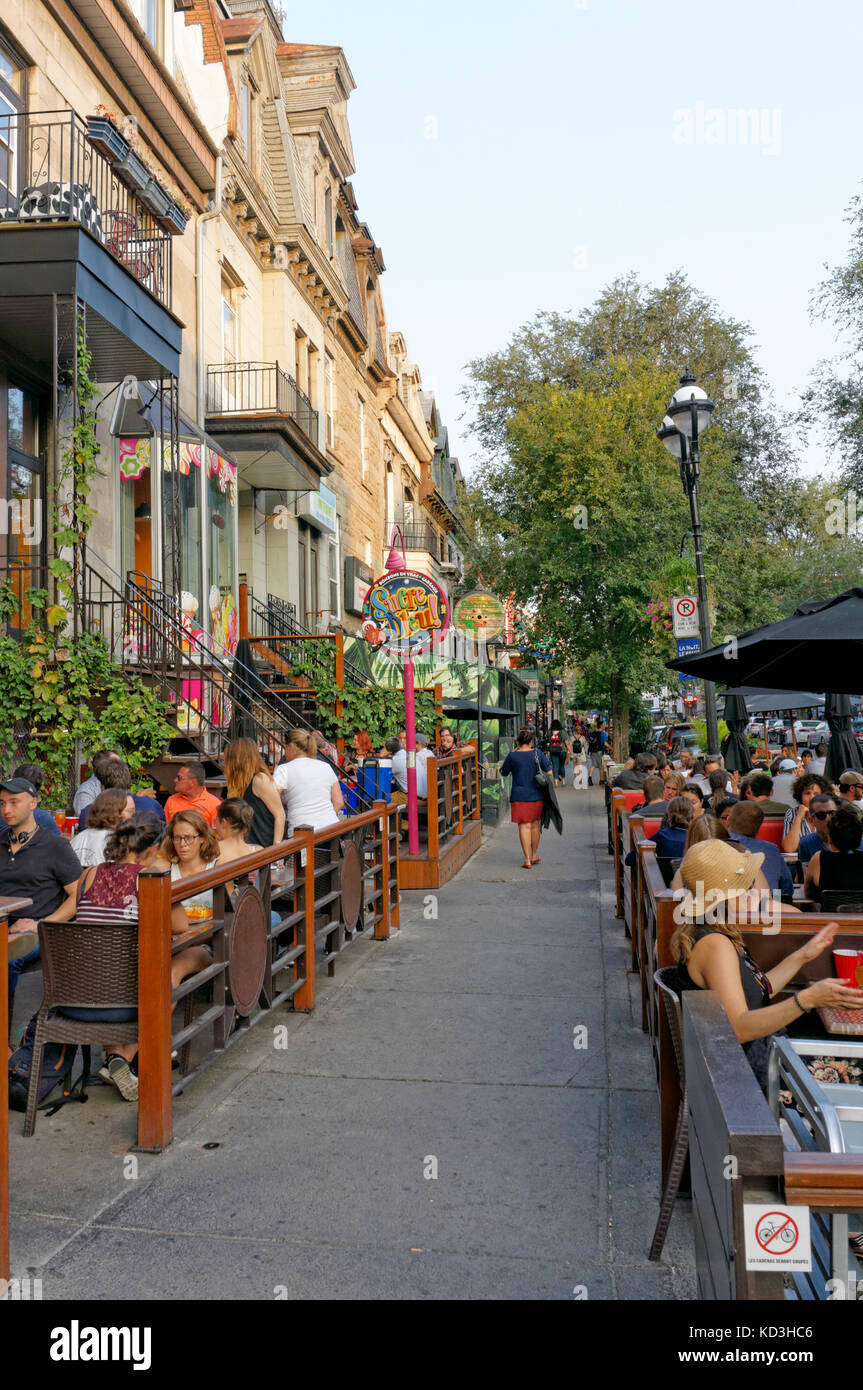 People sitting and talking in outdoor restaurants and bistros on Rue Saint Denis street, Latin Quarter, Quartier Latin, Montreal, Quebec, Canada Stock Photo