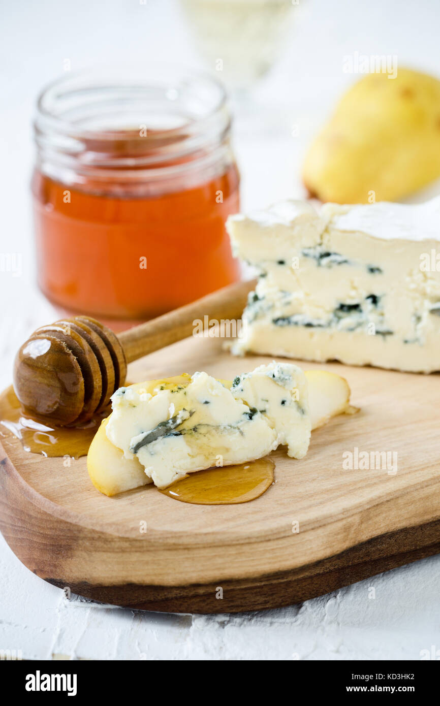 Blue cheese served with fresh pear and honey on rustic cutting board