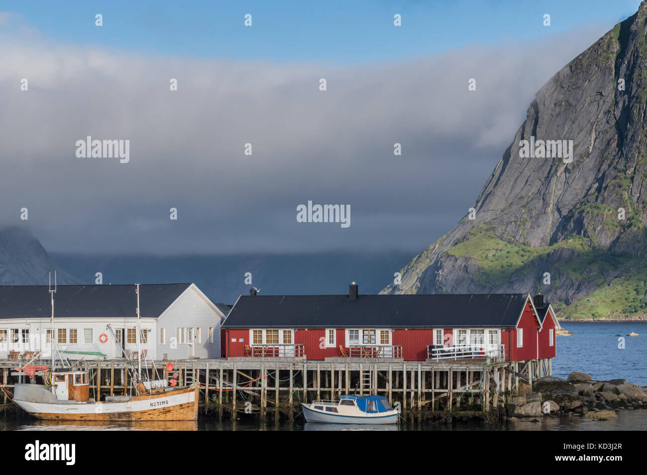 Traditional fisherman rorbu, cottage, huts in Lofoten Islands. Majestic mountains and clouds in the background Stock Photo