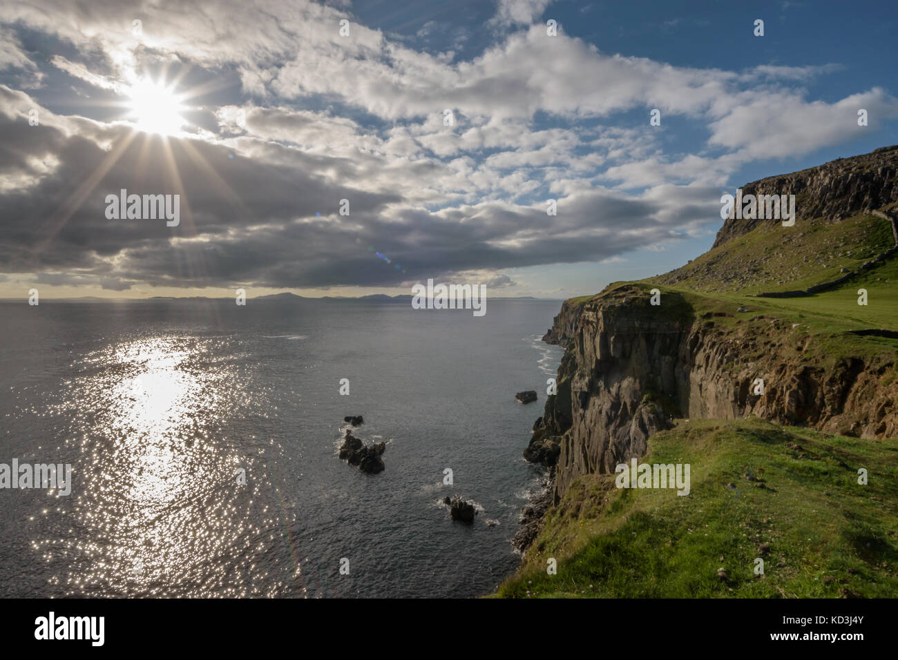 Sunset in Point Neist, Isle of Skye, Scotland. Dramatic high cliffs, sun reflections in water. Outer Hebrides in distance Stock Photo