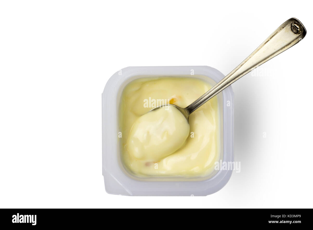 Creamy yellow apricot and peach yogurt in little plastic cup with small silver spoon - Top view image of fruit yoghurt in pot isolated on white backgr Stock Photo