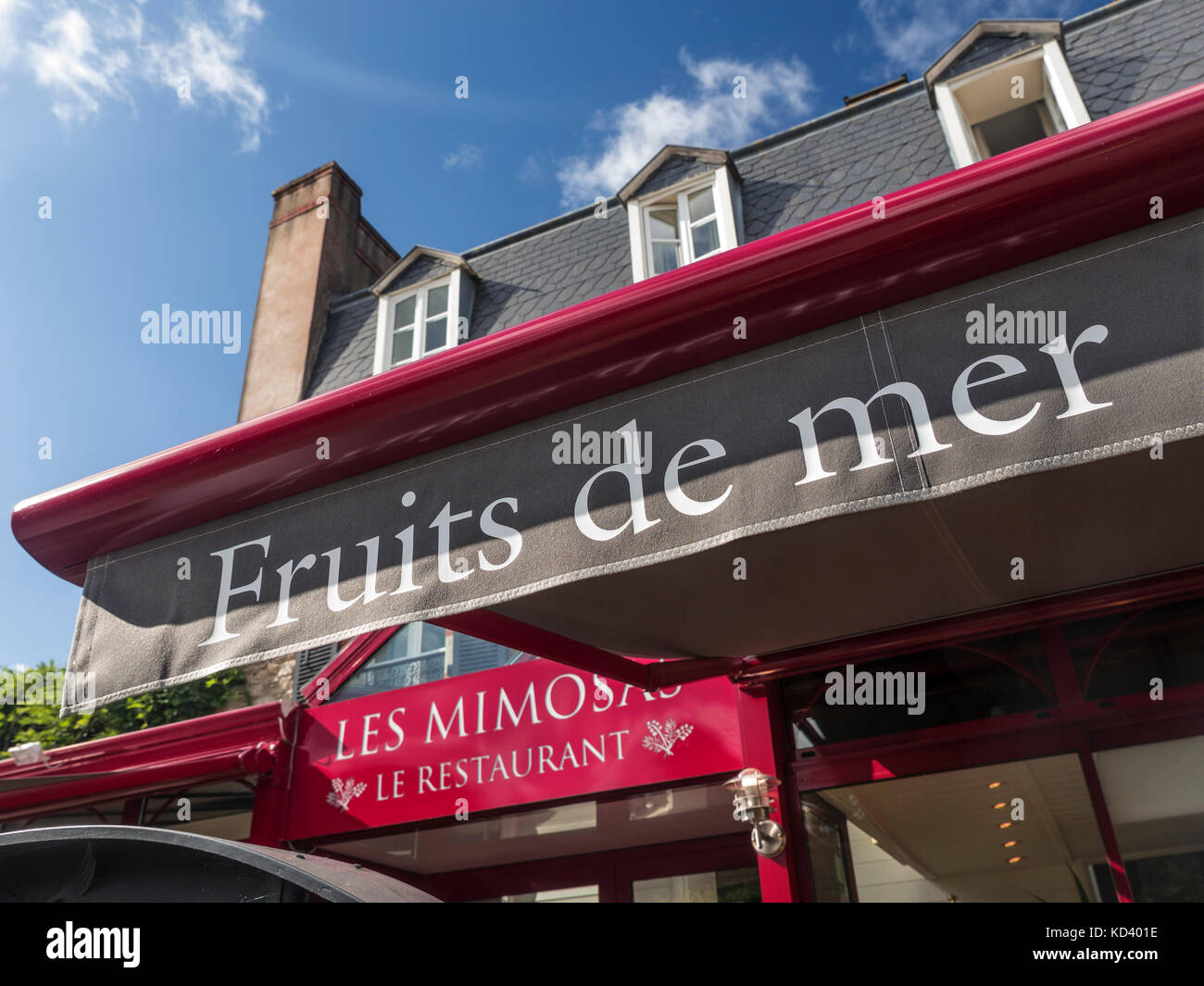 Close view on sunlit Les Mimosas Restaurant / Hotel terrace sunshade promoting local 'Fruits de Mer' seafood specialties in Pont-Aven Brittany France Stock Photo