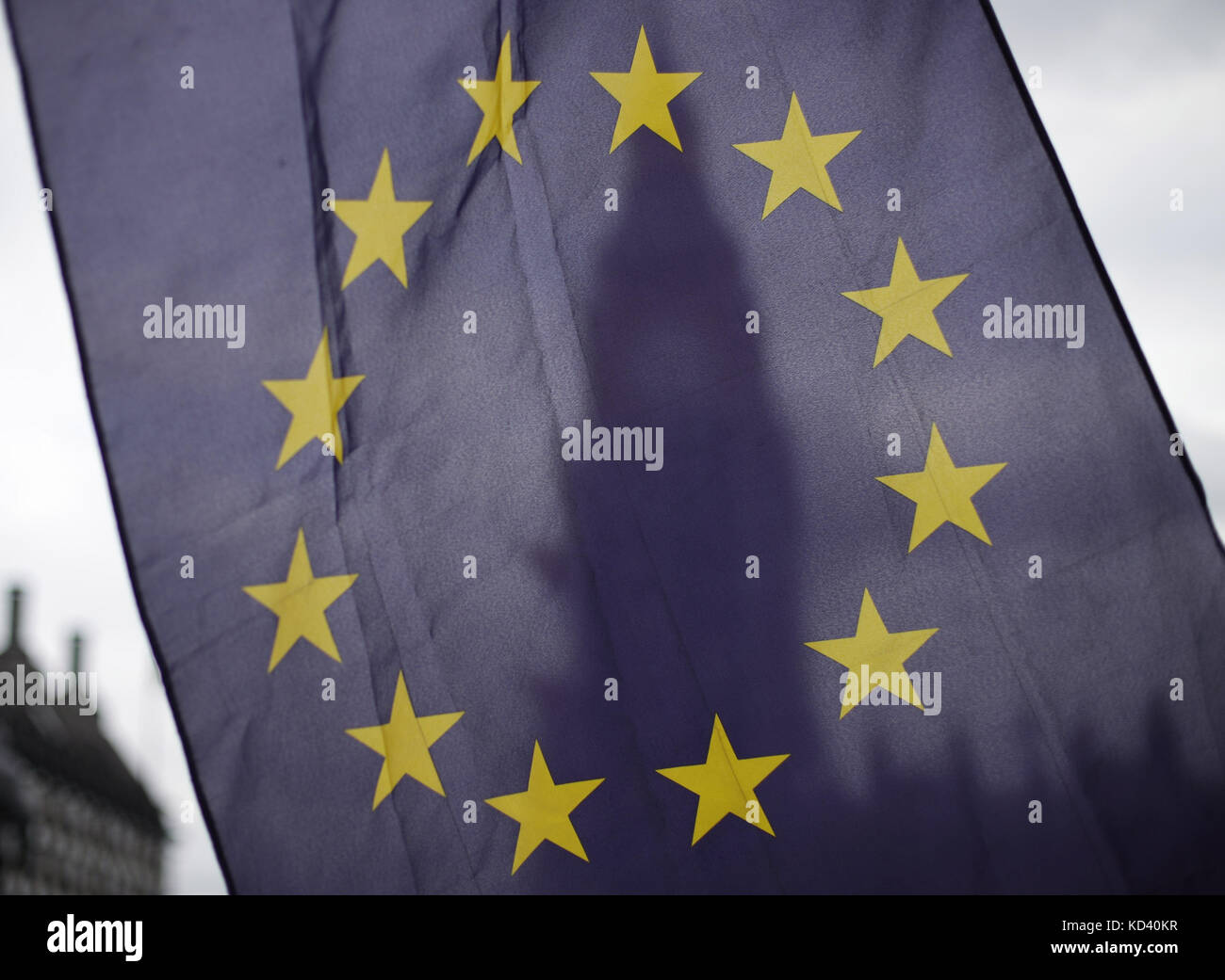 An EU flag is waved in front Big Ben and the Elizabeth Tower at the Houses Parliament in London, after Prime Minister Theresa May updated MPs in the House of Commons, London on the Brexit negotiations since her Florence speech last month. Stock Photo