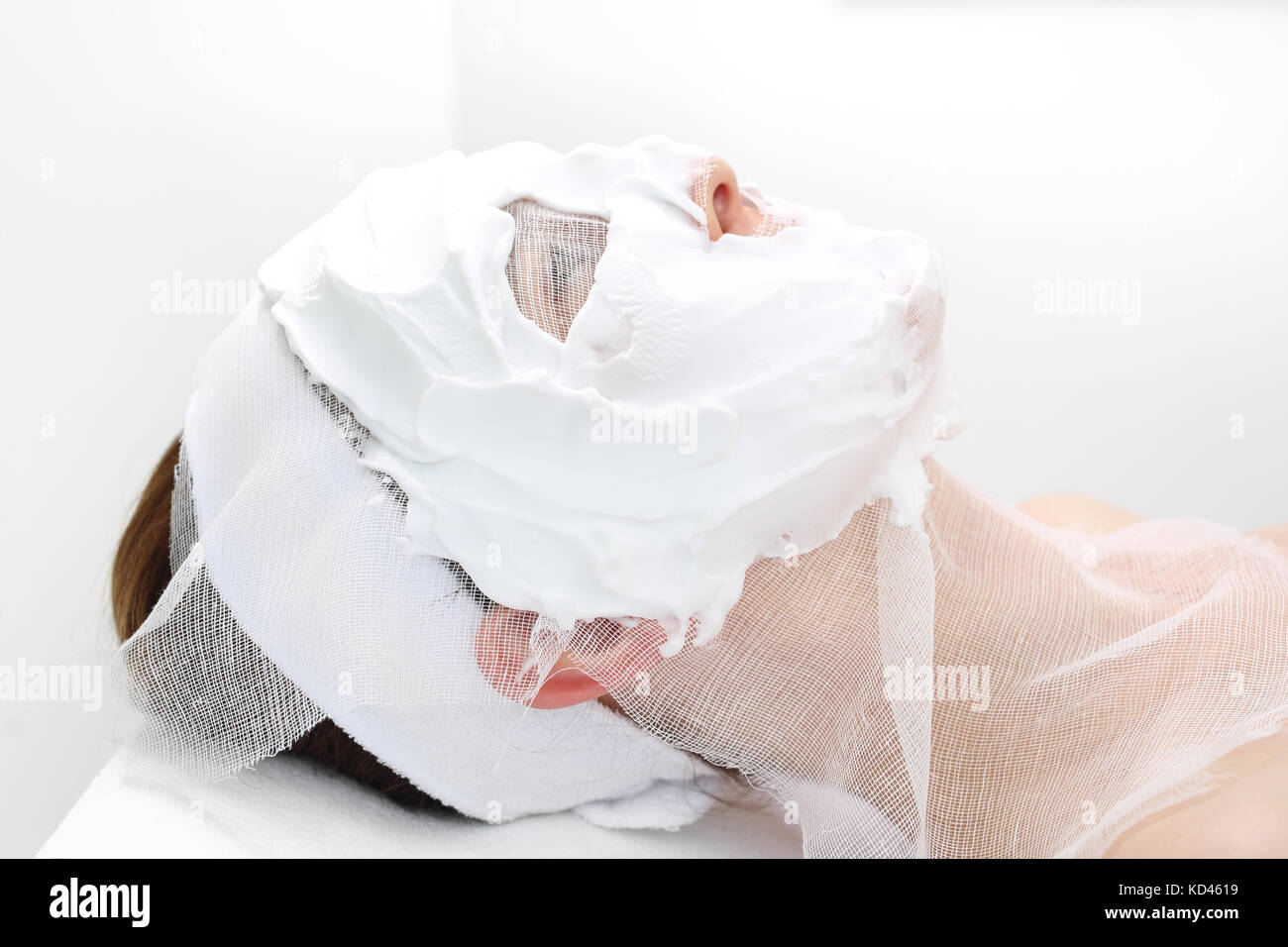 Skin care of the face in the beauty salon.  Beautician puts a mask on a woman's face. Woman in a beauty salon during a skin care treatment. Stock Photo