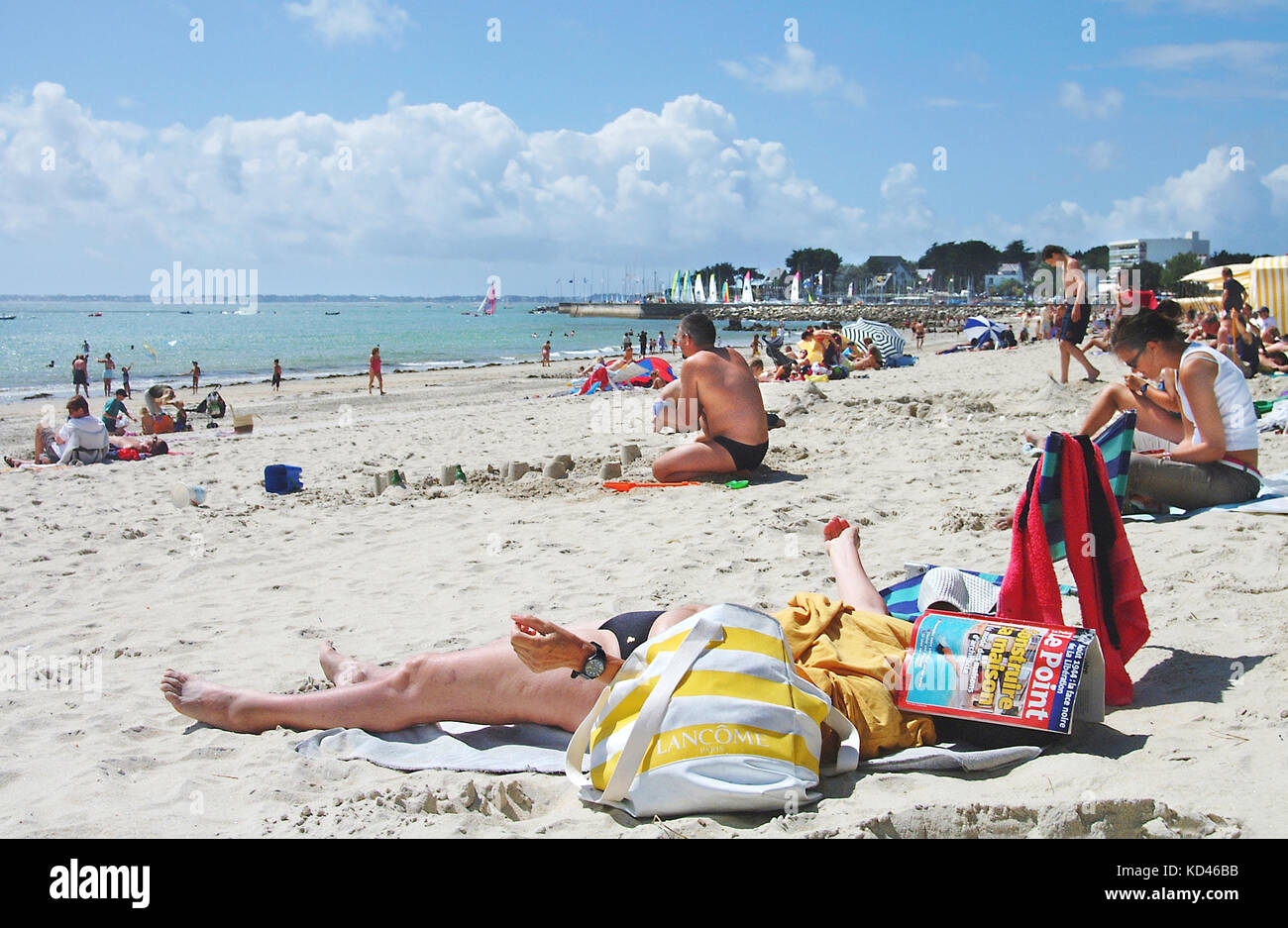 Candid picture of an old woman with Le Point magazine over her head sunbathing on Carnac beach, France. Stock Photo
