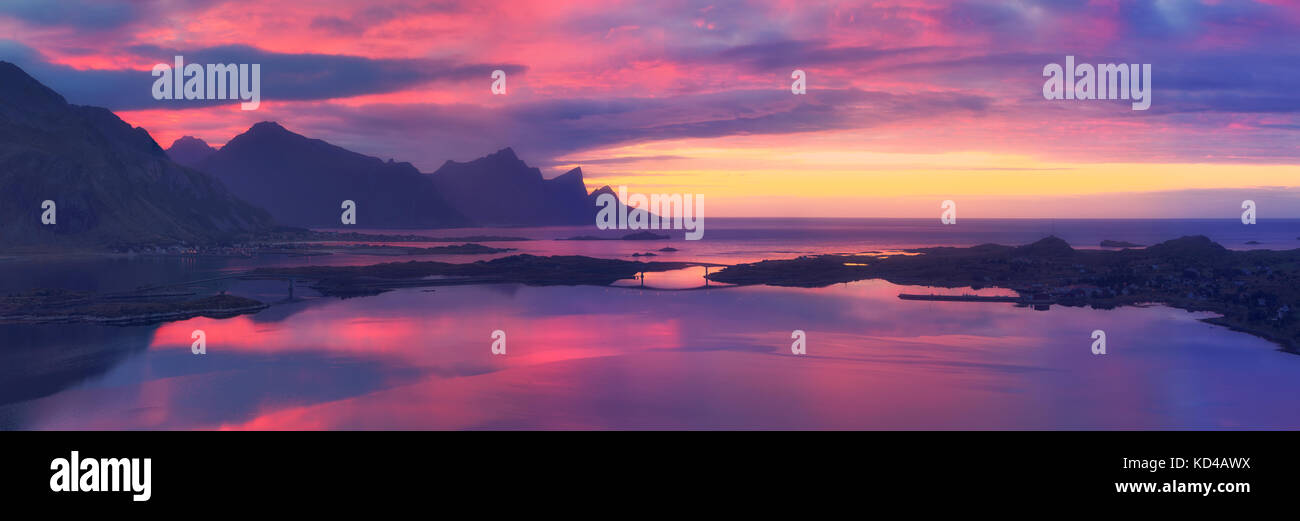 Gorgeous sunrise over sea. Purple sky and rocks reflected in sea water in the morning. Beautiful Norwegian landscape. Morning panoramic background. Stock Photo