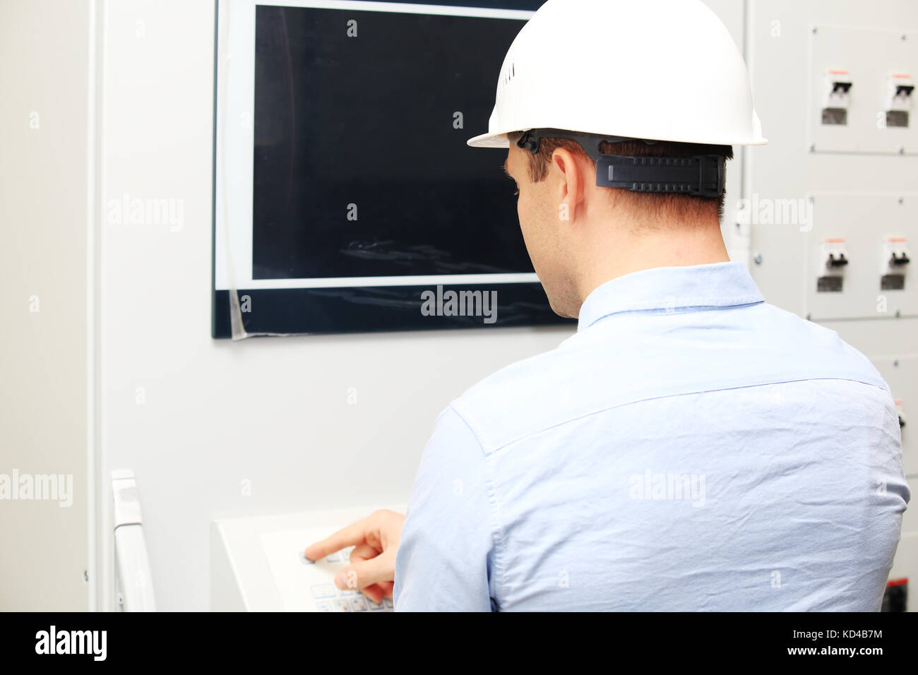 Engineer in hard hat at working place at power station. Engineer programing controllers. Stock Photo