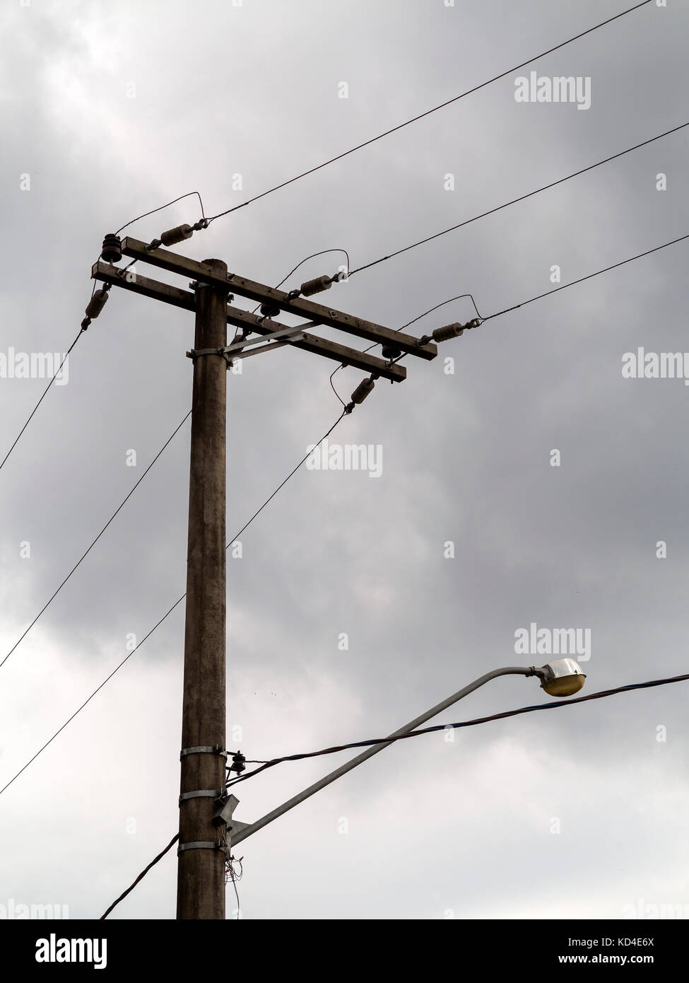 wooden electric post with wires and a lamp in a gray cloudy day Stock Photo  - Alamy