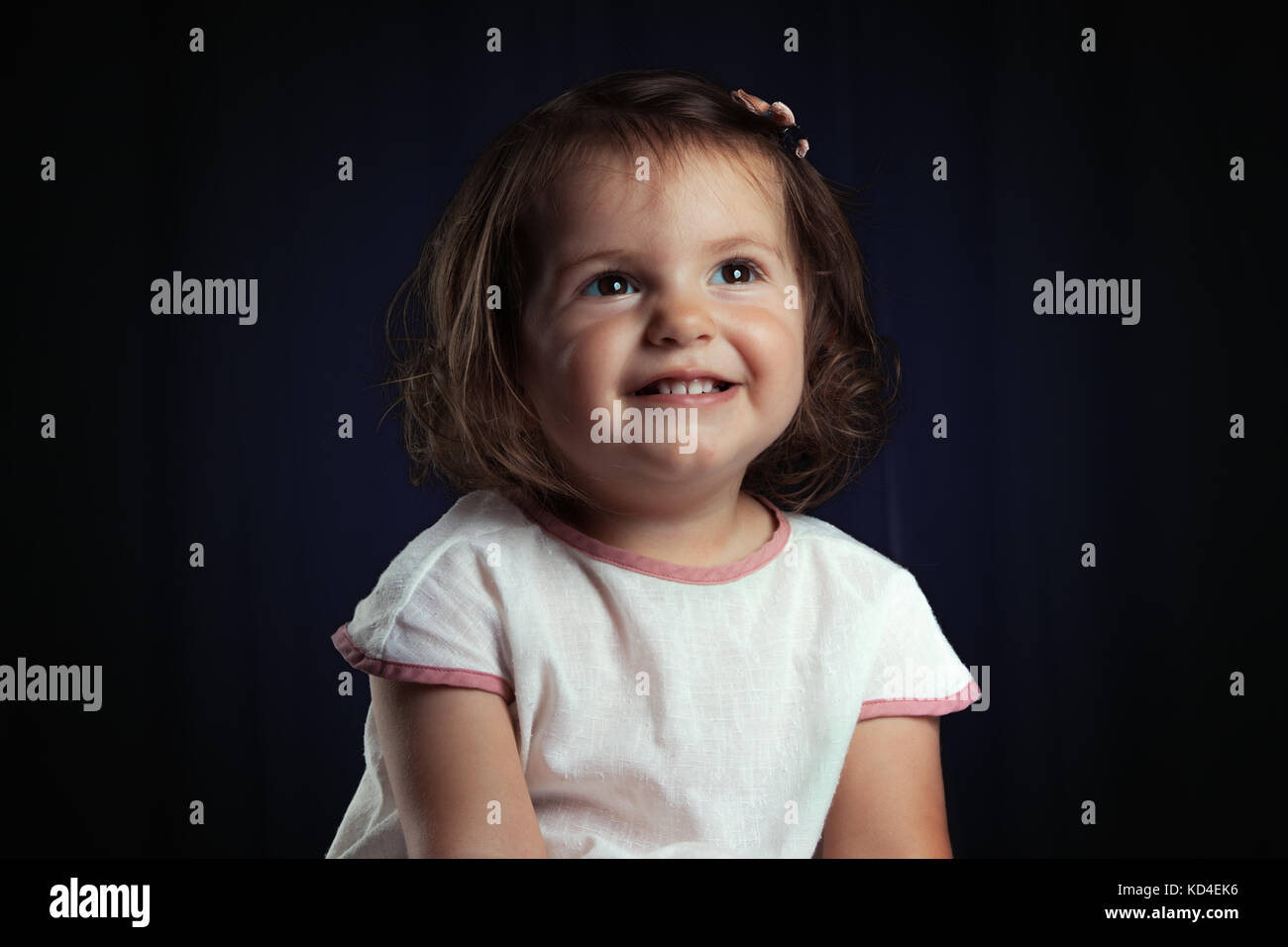 Portrait of a cute little smiling baby girl on black background Stock Photo