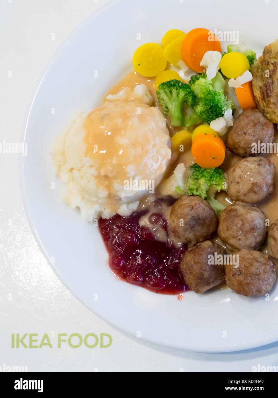 A plate of IKEA meatballs, mashed potatoes, cream gravy, lingonberry sauce, mixed vegetables and a potato-vegetable medallion (grönsakskaka). Stock Photo