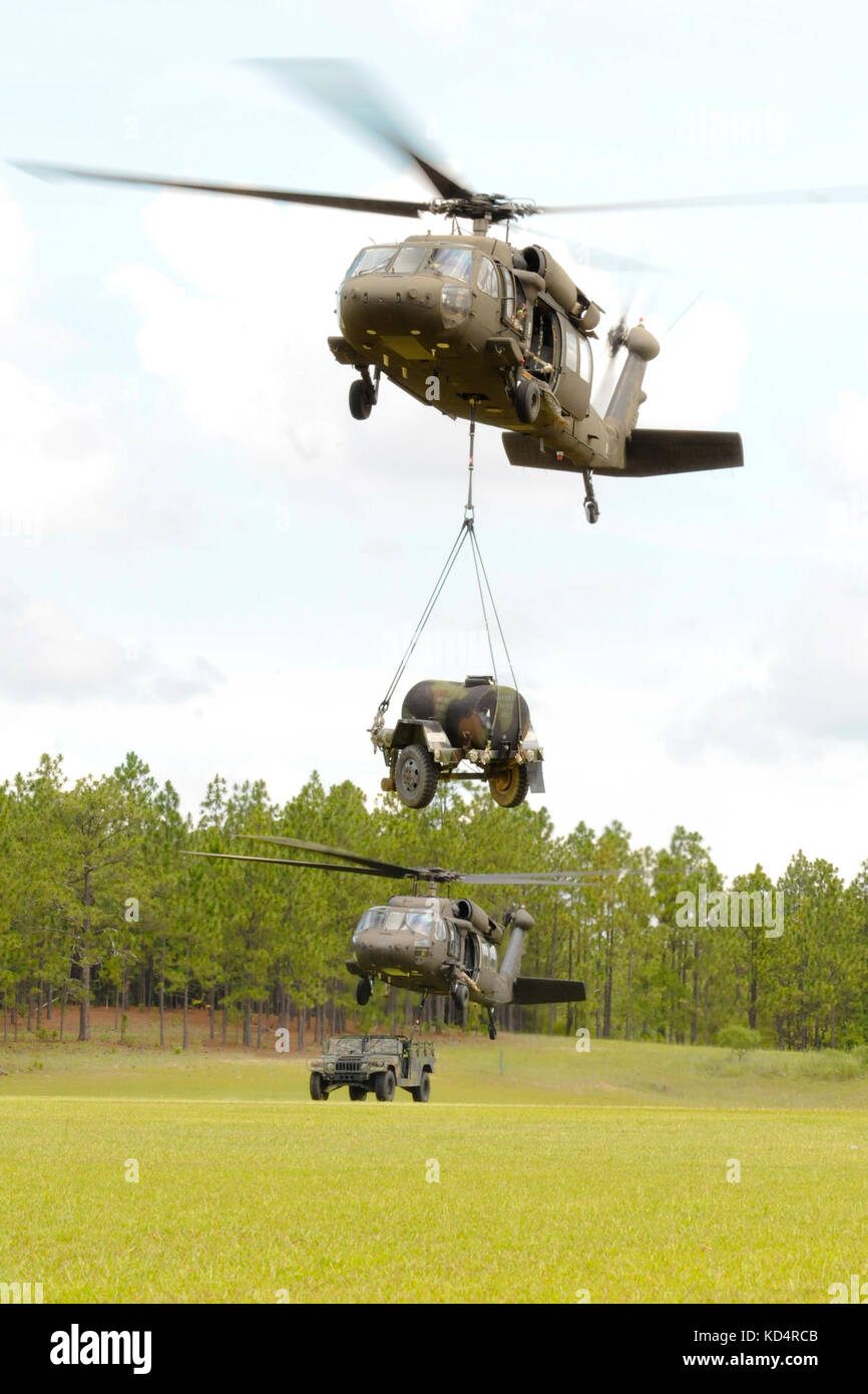 U.S. Army Soldiers with the 351st Aviation Support Battalion, S.C. Army National Guard, hook up a humvee and water buffalo to Black Hawks to practice sling load operations at Fort Jackson, July 13, 2014.  The training is part of the unit’s pre mobilization preparedness for their upcoming deployment to Kuwait. (U.S. Army National Guard photo by Sgt. Brian Calhoun/Released) Stock Photo