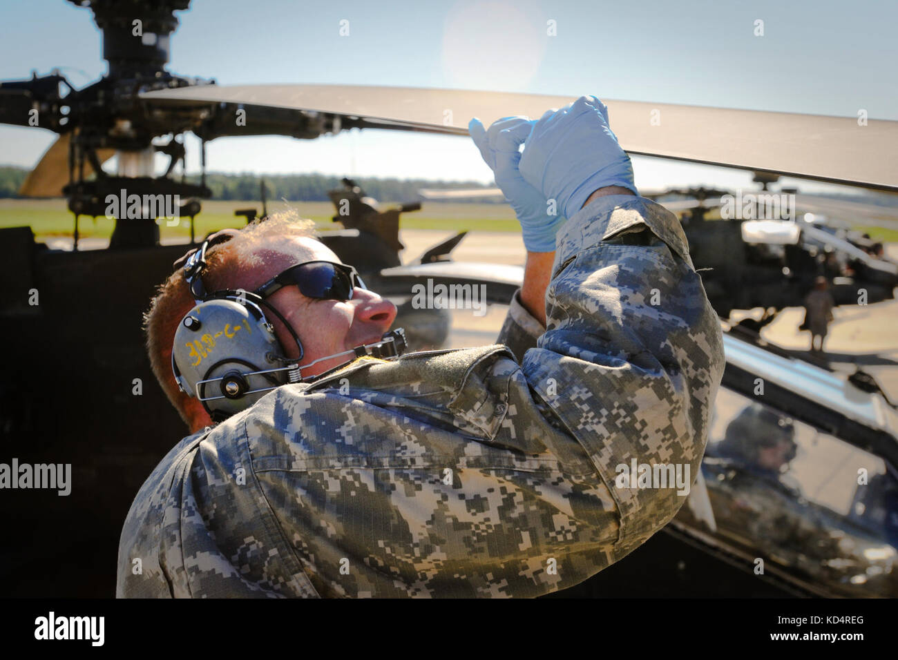 Sgt. Jacob Reese, a AH-64D “Apache” Attack Helicopter Repairer, with the S.C. Army National Guard’s 1-151 Attack Reconnaissance Battalion, installs a blade wedge on the main rotor of the aircraft, Oct. 5, 2014, at McEntire Joint National Guard Base.  Maintainers install blade wedges on the highly sensitive main rotors to reduce vibration and to increase smoothness of flight.  (U.S. Army National Guard photo by Sgt. Brian Calhoun/Released) Stock Photo